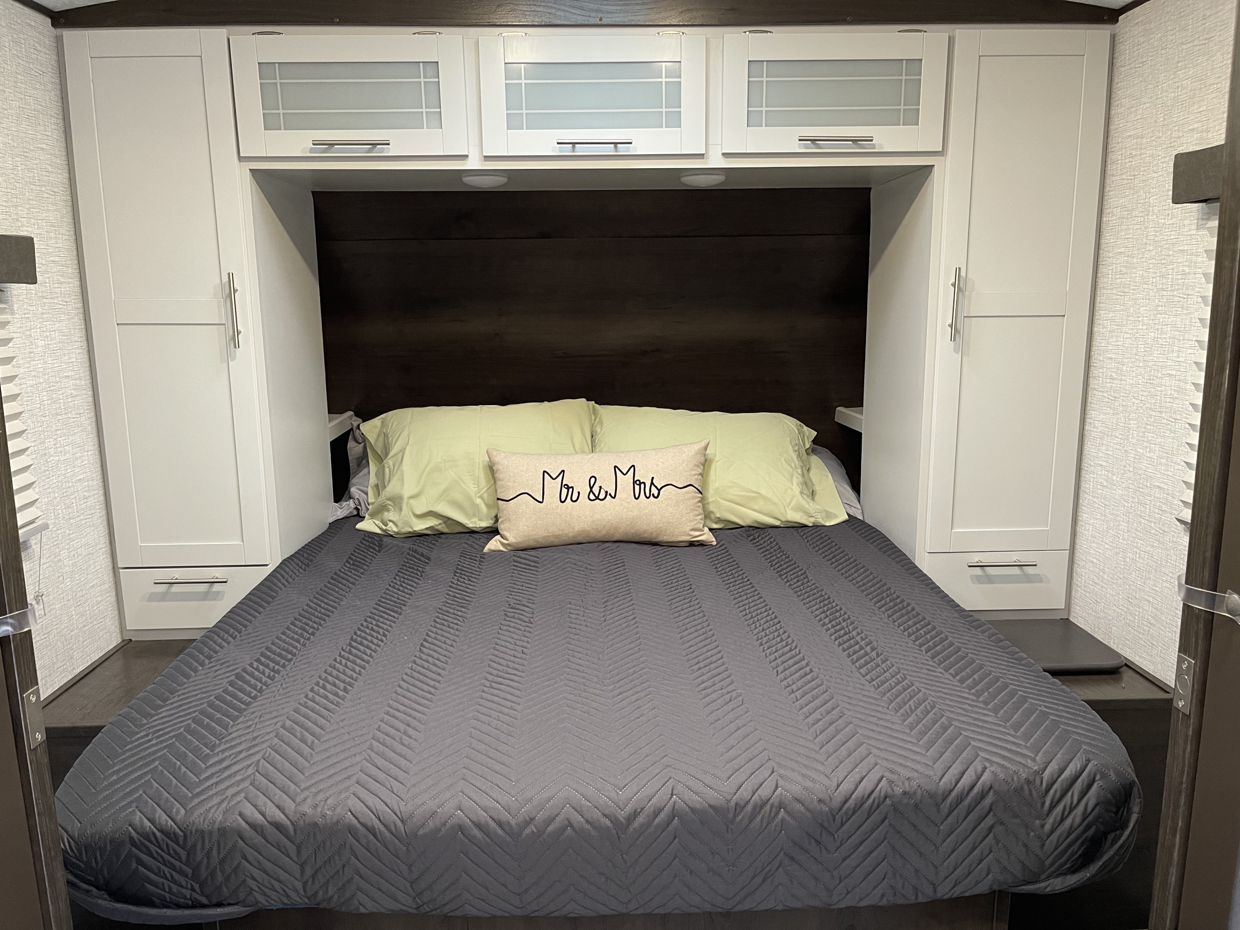 Compact RV rental bedroom with a comfortable bed, overhead storage cabinets, and side wardrobes for a convenient stay.. Keystone RV Bullet Ultra Lite 2021