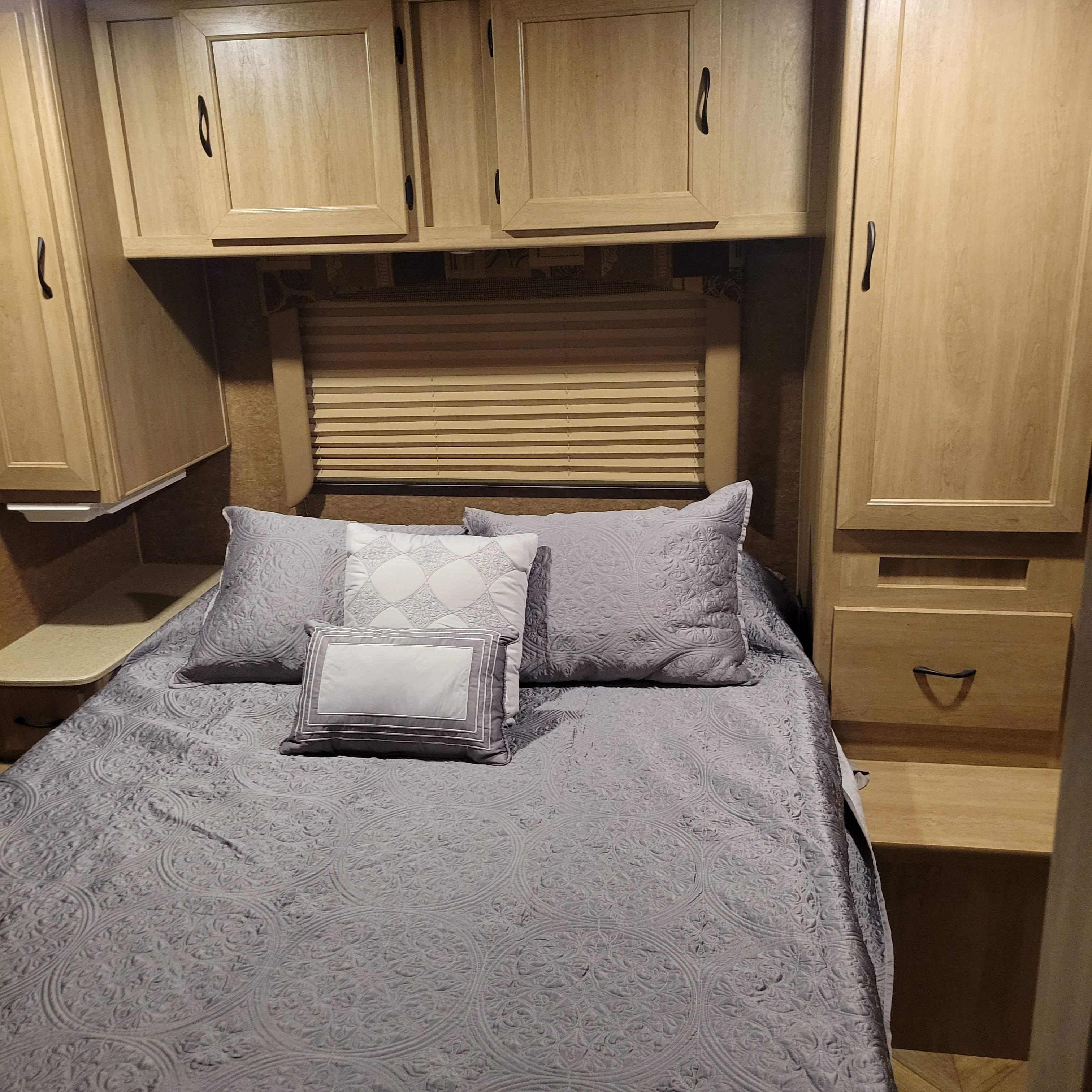 Cozy RV bedroom with gray bedding, built-in storage, and window blinds, perfect for an RV rental.. Forest River Coachmen Freelander 2016