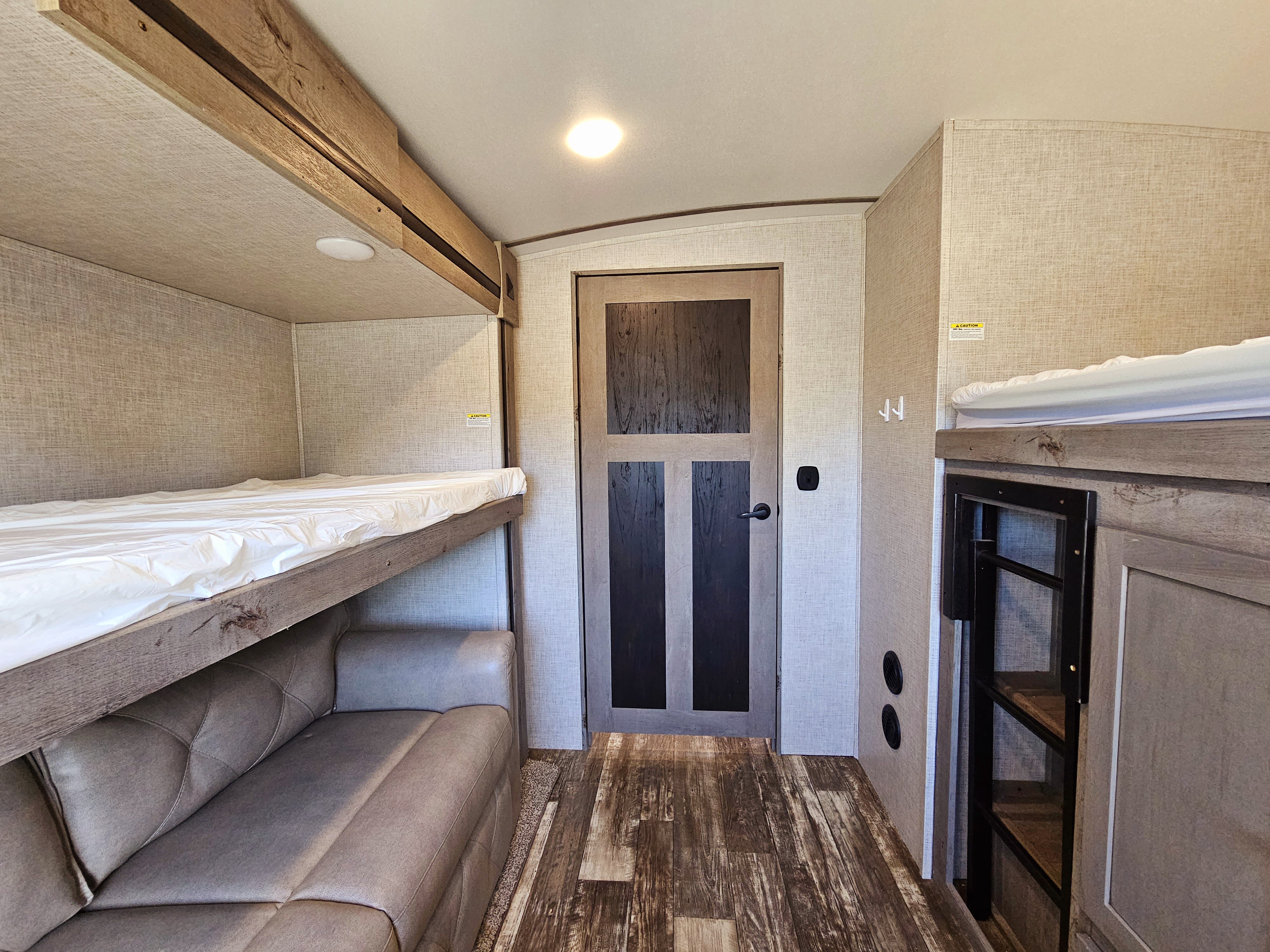 RV rental interior featuring bunk beds and a sofa, designed as a compact living and sleeping area for travel.. Keystone Outback 2020