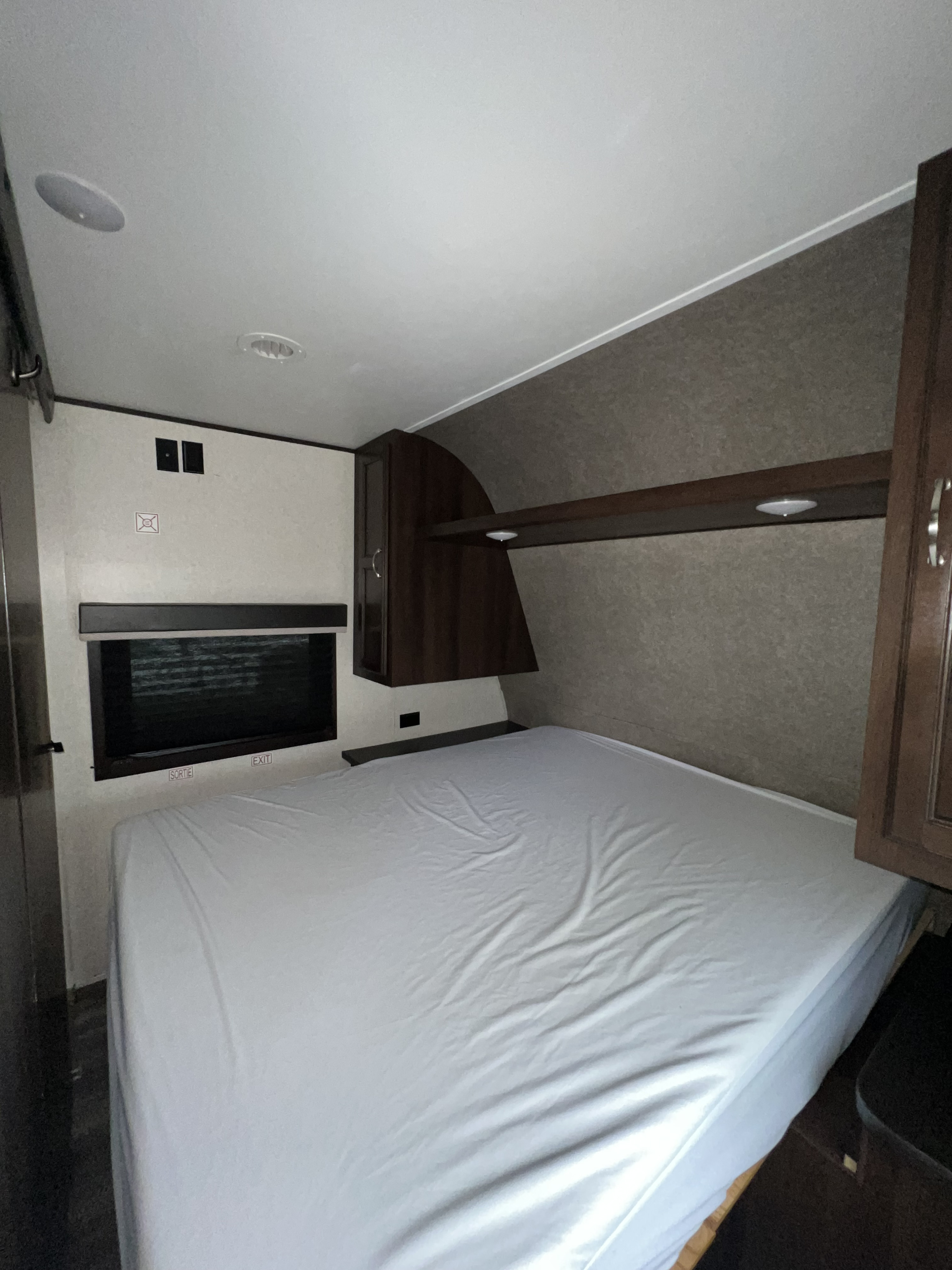 RV rental: Cozy bedroom showing a bed with white sheet, emergency exit window, and wood cabinetry.. Jayco Jay Flight 2018