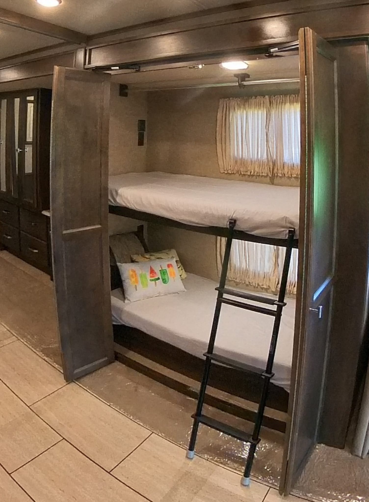Cozy bunk beds in this RV rental's inviting interior, complete with a ladder, window curtains, and ample storage for travel.. Allegro Allegro Open Road 2018