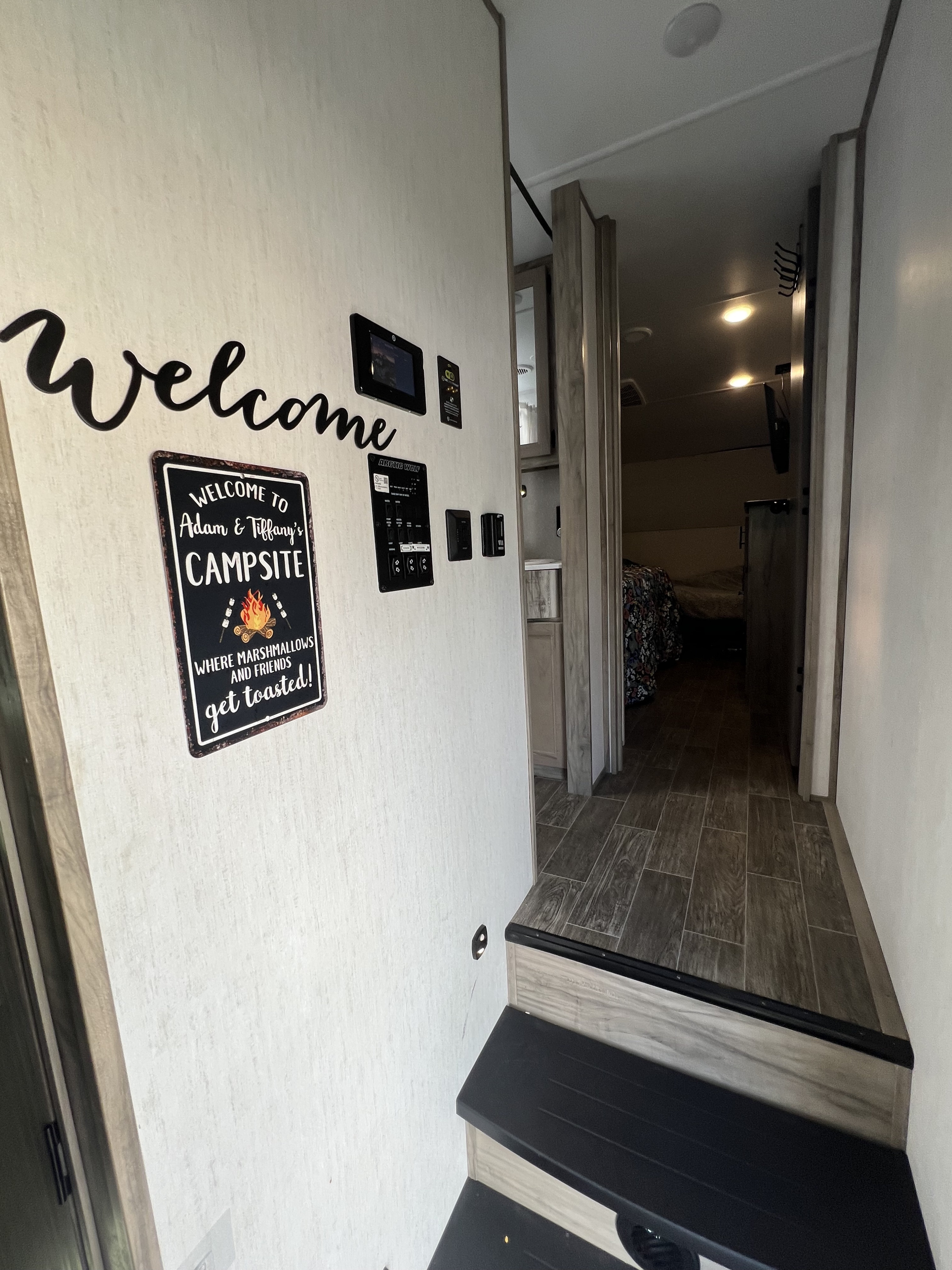 Inside a welcoming rv rental with steps leading into the living space, featuring custom camping signs and control panels.. Forest River Wolf Pack 2021