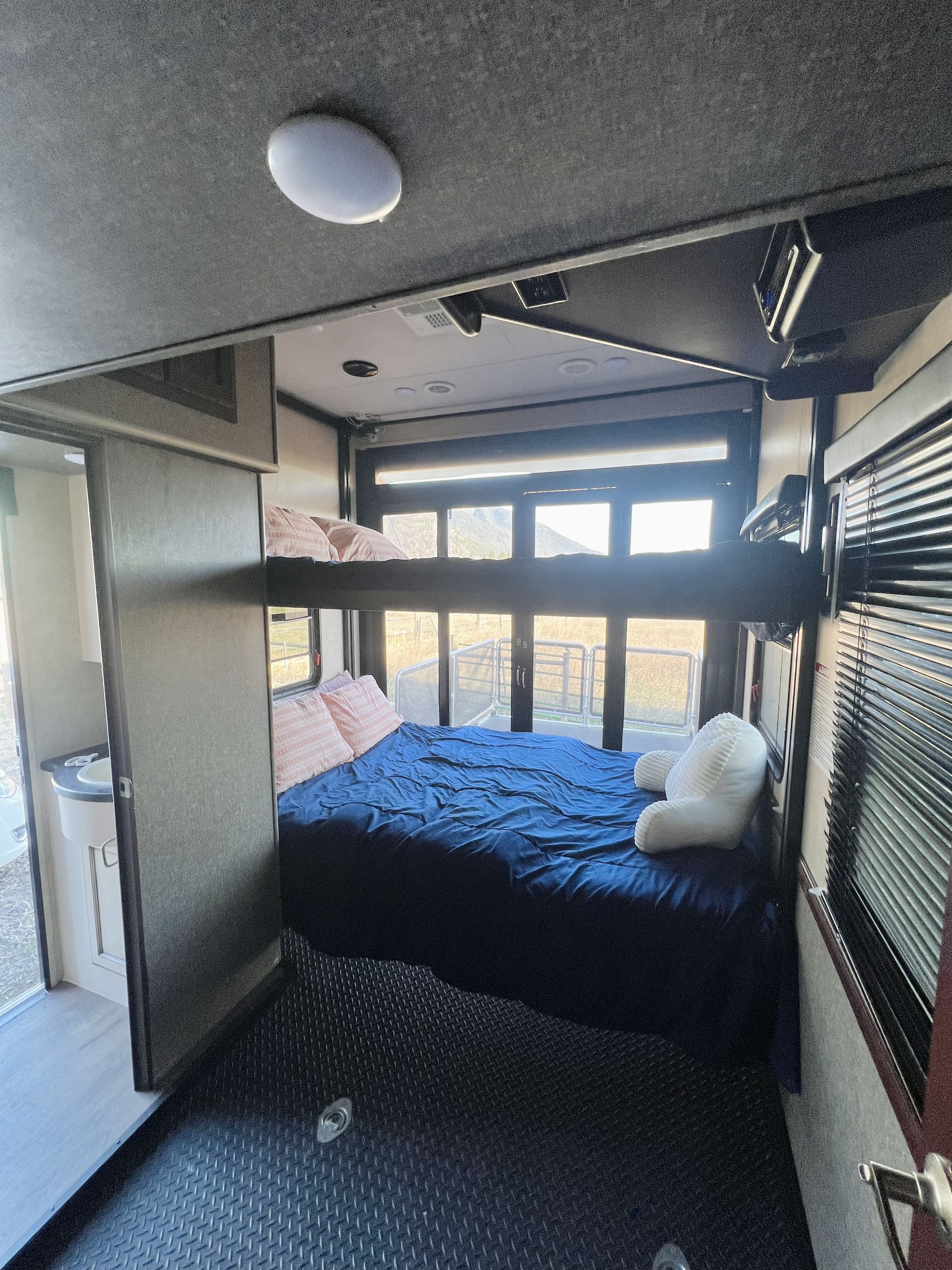 Spacious RV rental interior with bunk beds, bright windows, a sink, and rugged diamond-plate flooring.. Heartland RVs Road Warrior Toy Hauler 2015