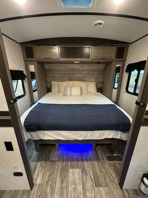 Cozy RV rental bedroom with blue under-bed lighting, overhead storage, and window views. Perfect for your next trip.. Crossroads RV Sunset Trail Super Lite 2021