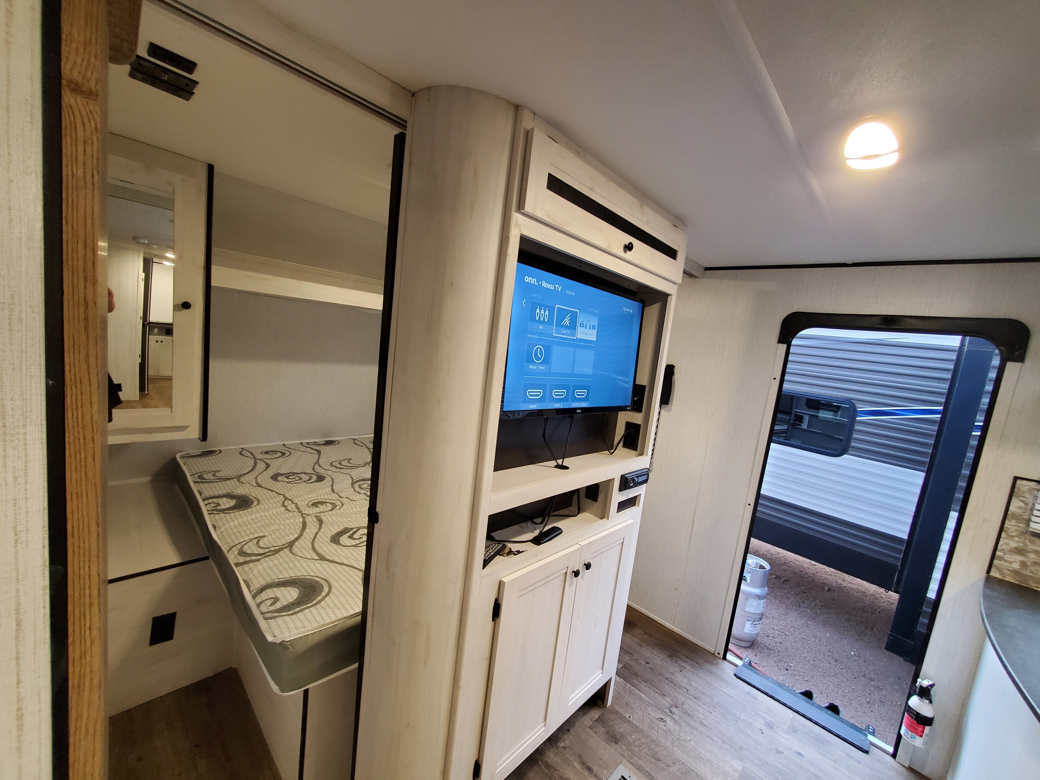 Explore this cozy rv rental interior, featuring a comfortable bed and an entertainment center with a Roku TV.. Heartland Trail Runner 2021