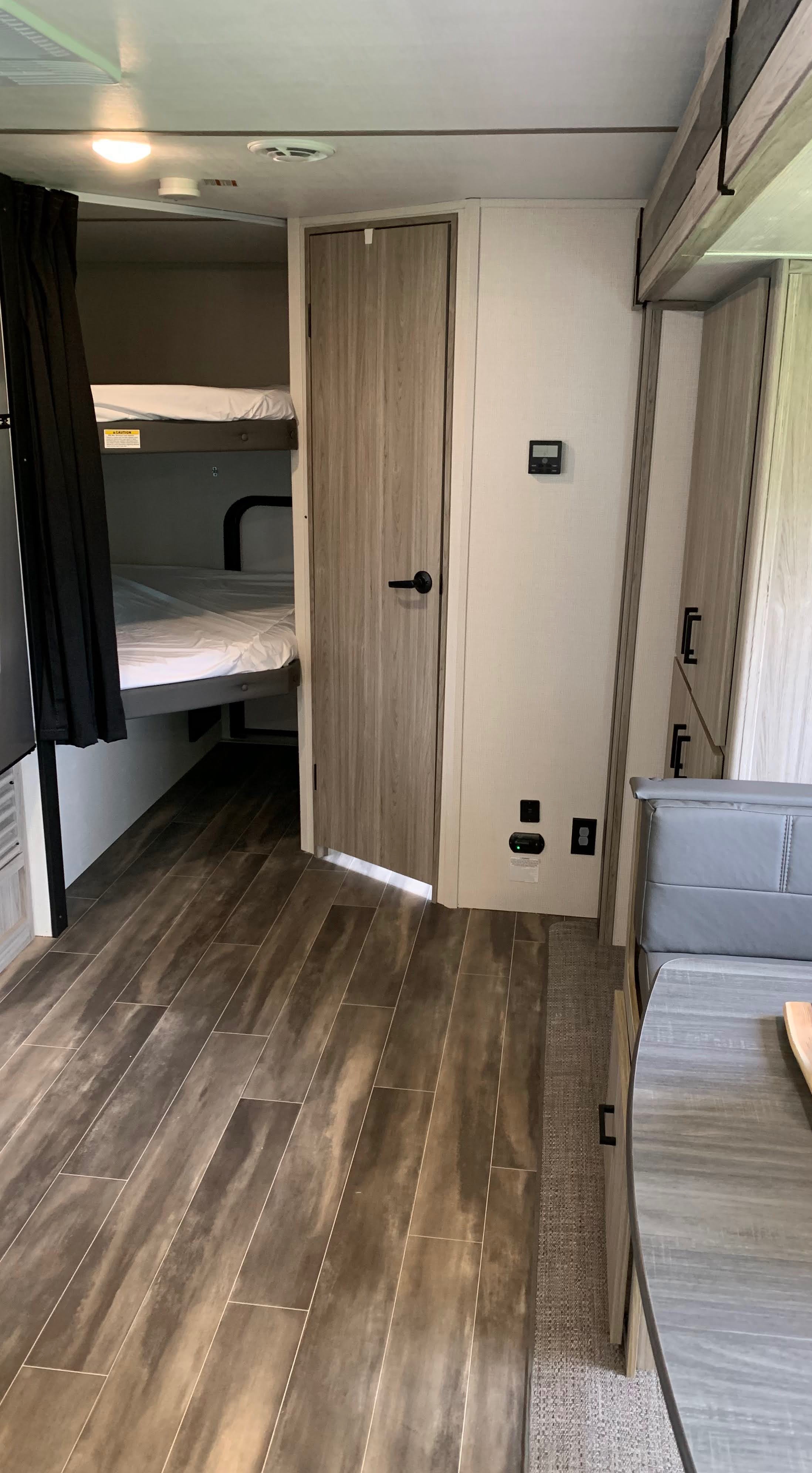 RV rental interior: bright, modern space with wood-look flooring, cozy bunk beds, and a dinette.. Keystone RV Passport SL 2022