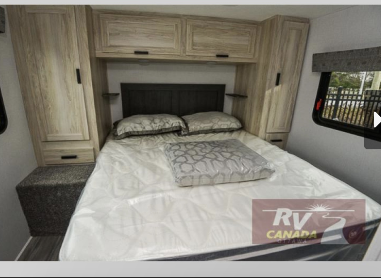 Cozy RV rental bedroom with a comfortable bed, light wood cabinets, and a window. Ideal for travelers.. Forest River Sunseeker LE 2023