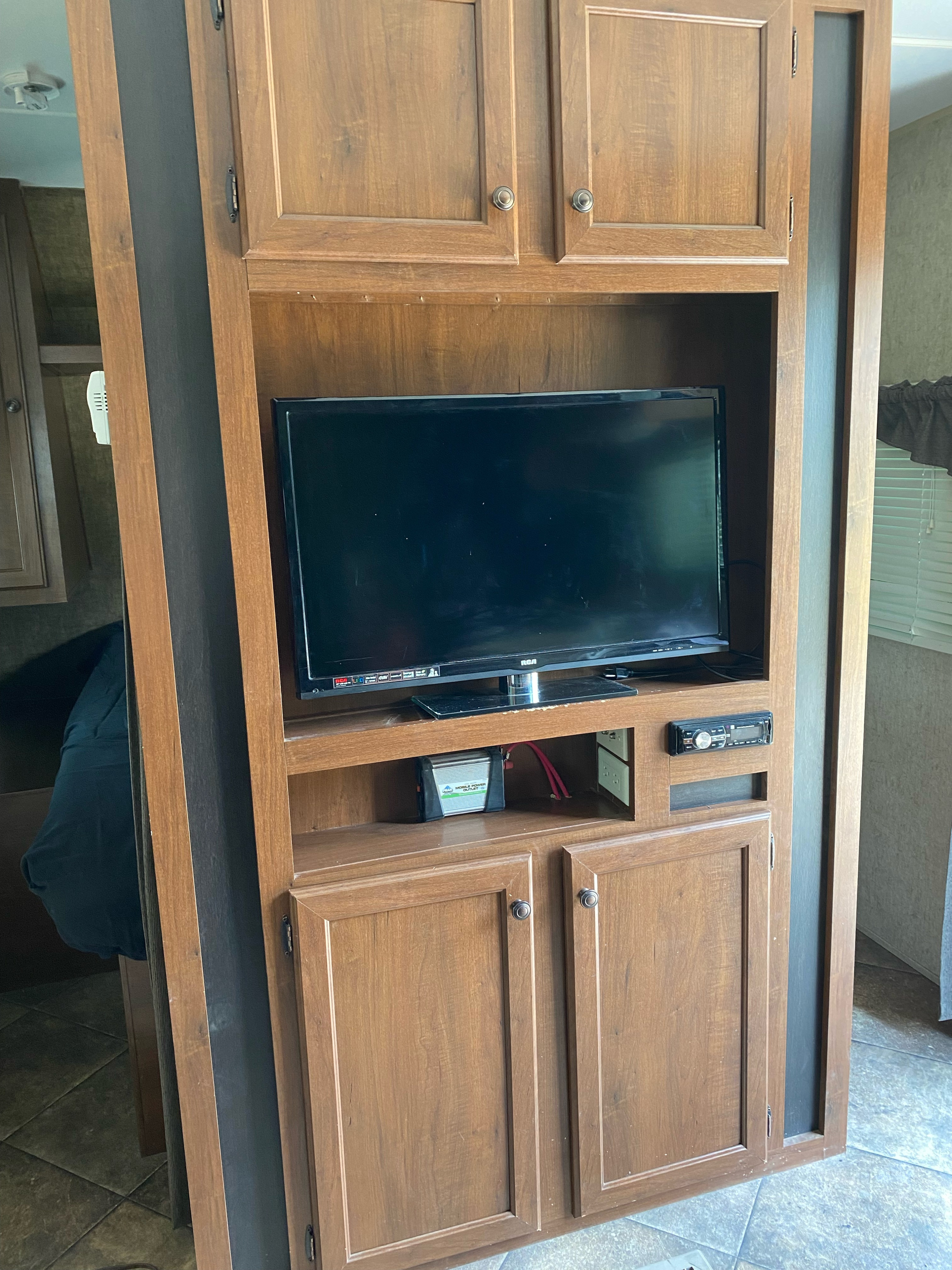 This RV rental features a wooden entertainment center with an RCA TV, stereo system, and mobile power inverter.. Heartland RVs 30LX 2014