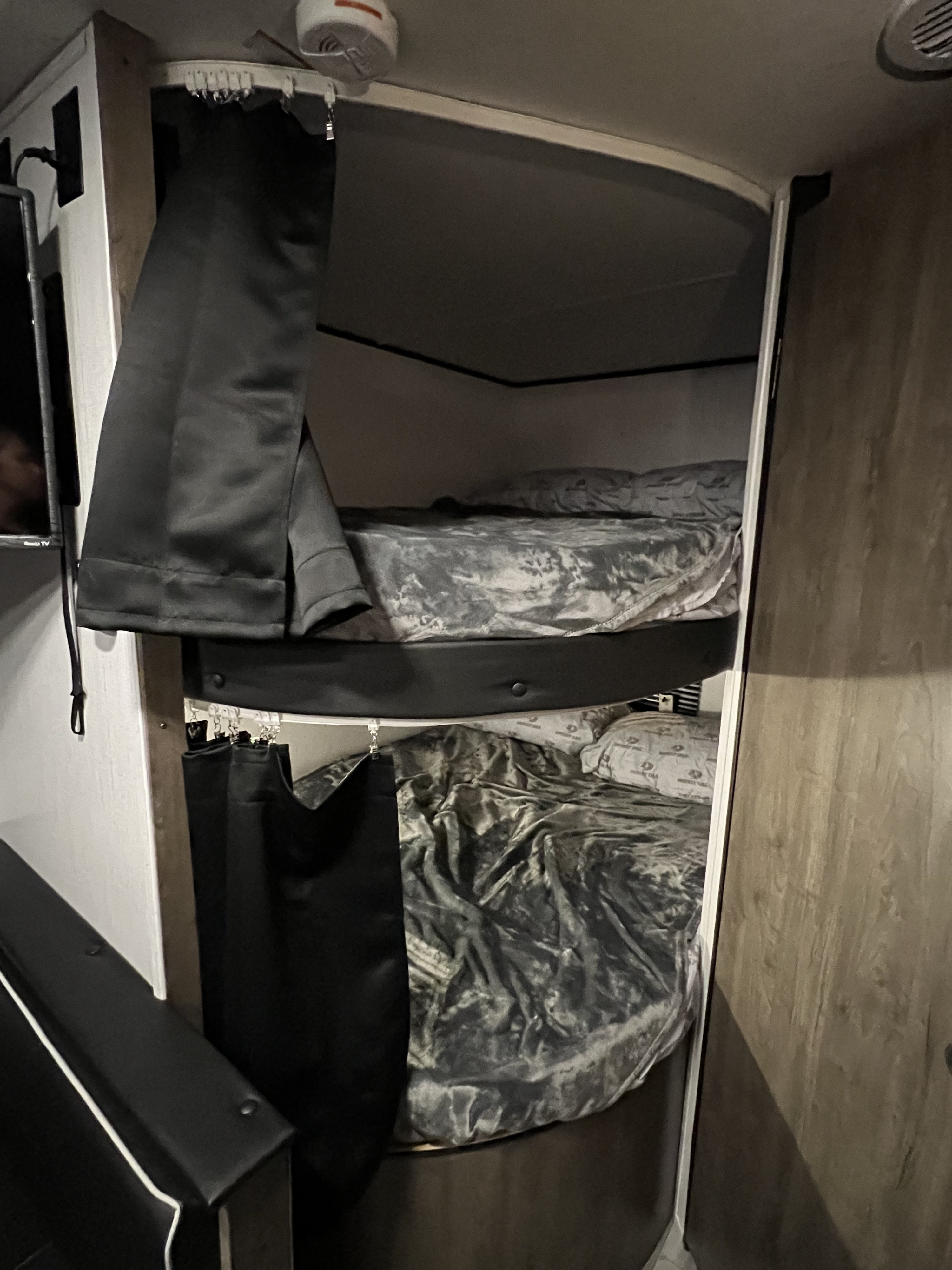 RV rental sleeping area: stacked bunk beds with dark grey bedding and black privacy curtains, designed for compact comfort.. Heartland RVs Pioneer 2023