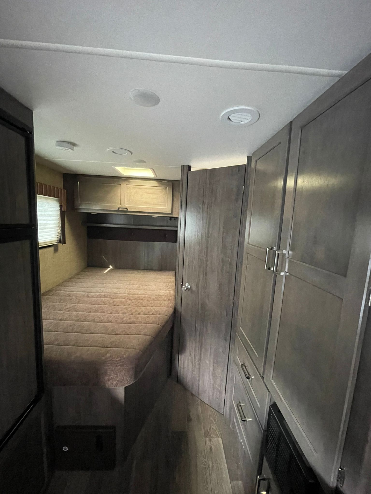 Inside this RV rental: a compact bedroom with a bed, window, and built-in cabinets, optimizing space for travel.. Winnebago Minnie Winnie 2019