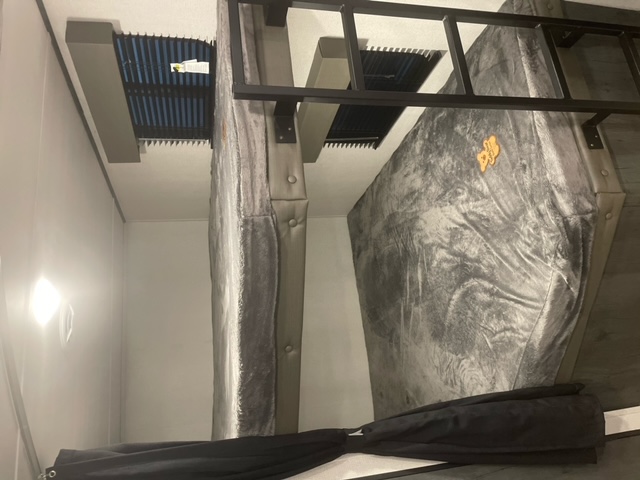 Spacious grey bunk beds are ready for guests in this RV rental's sleeping area, featuring a ladder and windows.. Keystone RV Hideout 2022