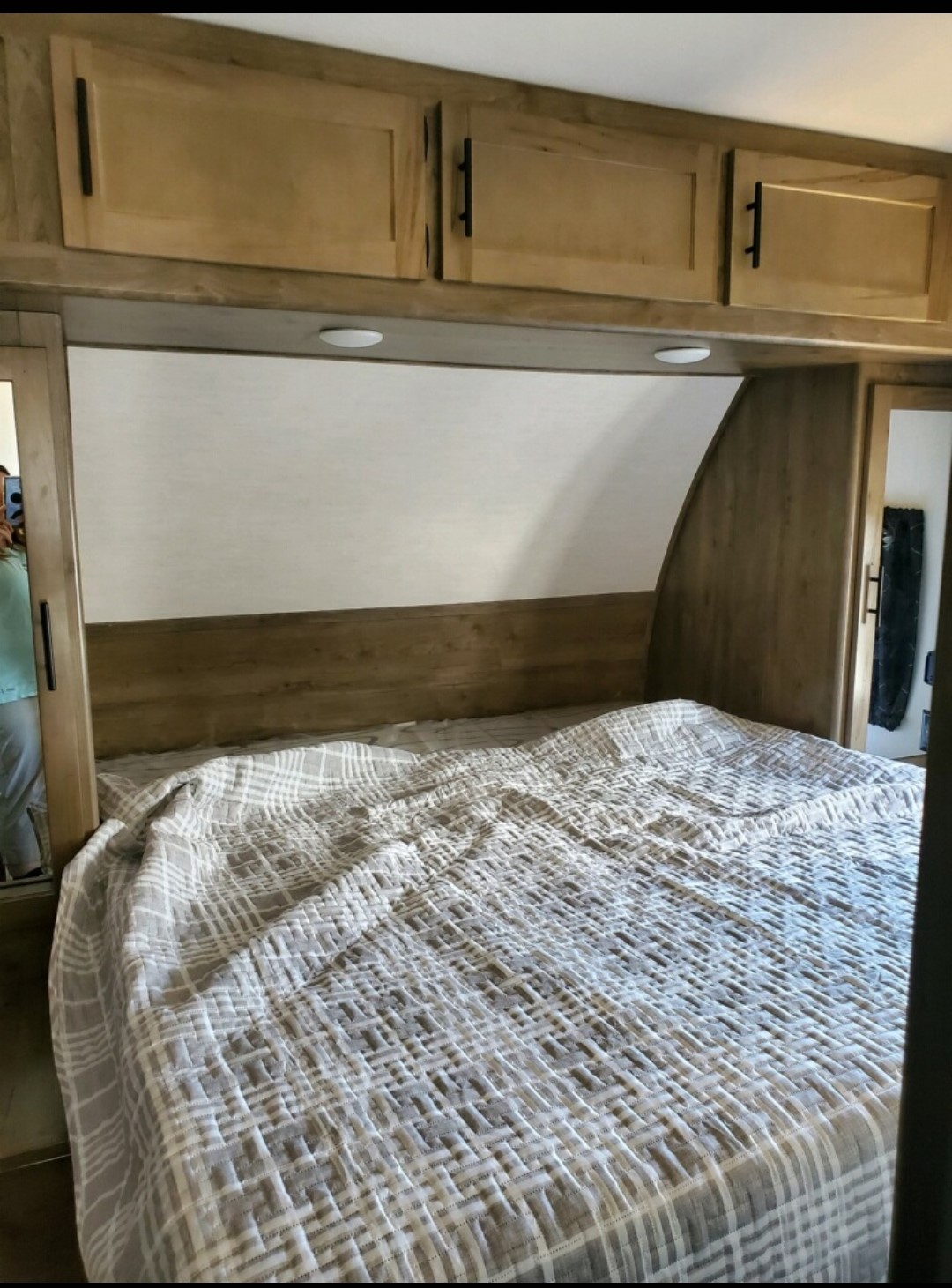Inside a comfortable RV rental bedroom featuring a plaid-patterned bed, wood cabinets, and task lighting.. Forest River Cherokee Wolf Pack Toy Hauler 2022