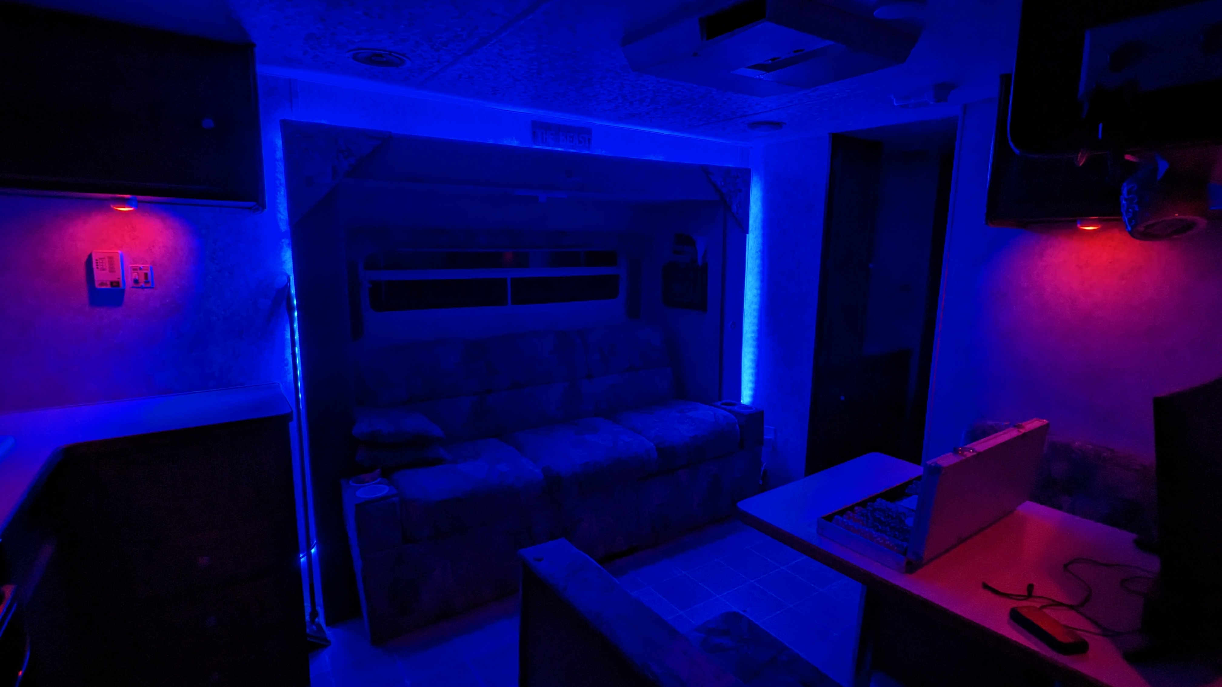 RV rental interior transformed with vibrant blue and red lighting, featuring a sofa-bed and workstation for entertainment.. Forest River Wildwood 2005