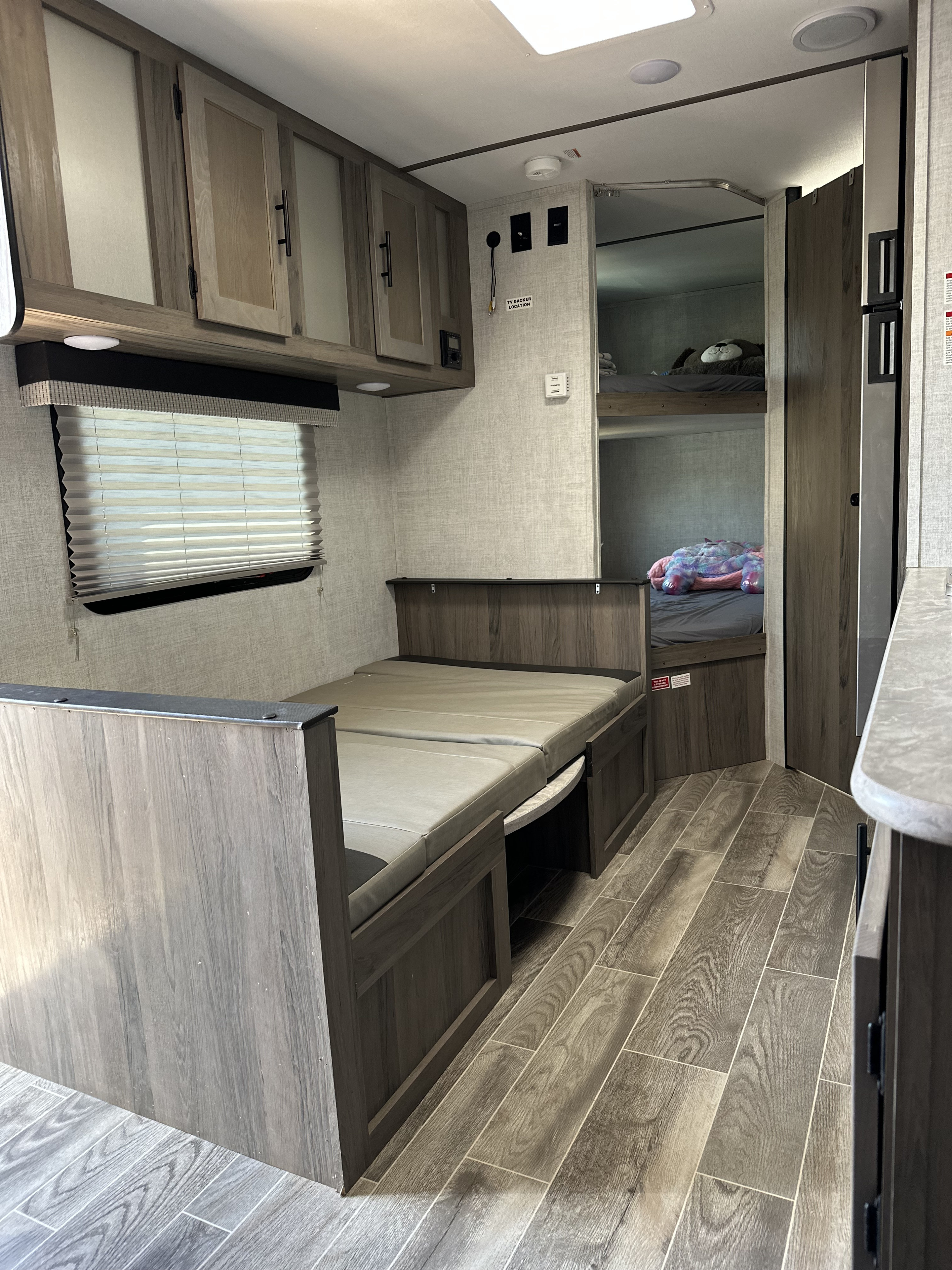 Inside this RV rental: a flexible dinette bed, bunk beds for guests, ample storage, and modern wood-style flooring.. Gulf Stream Ameri-Lite Super Lite 2022