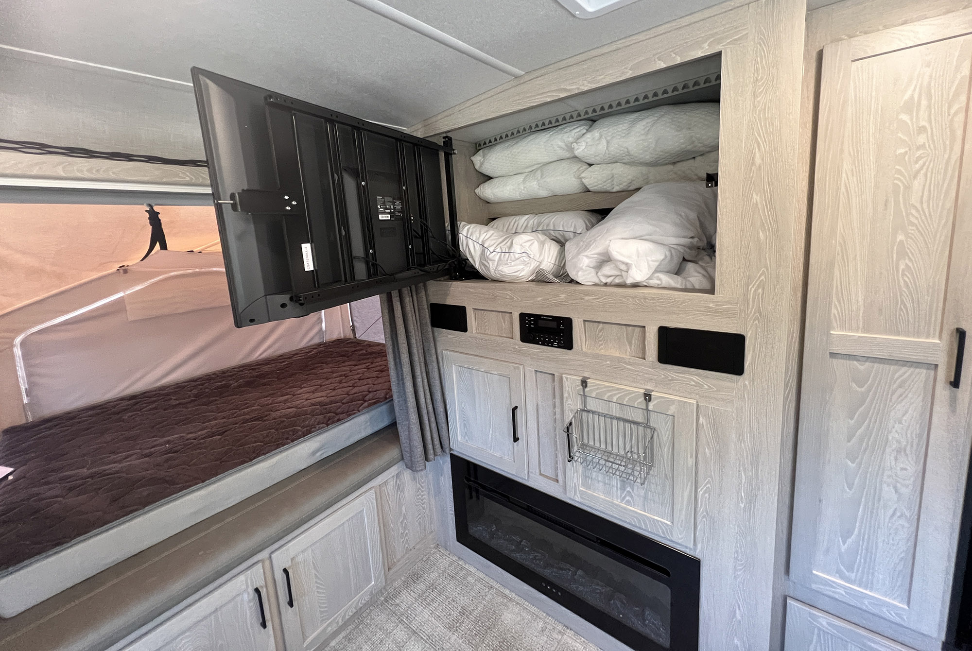 Explore this RV rental's interior: swing-out TV, overhead bedding storage, cabinets, and a modern electric fireplace.. Forest River Rockwood Roo 235S