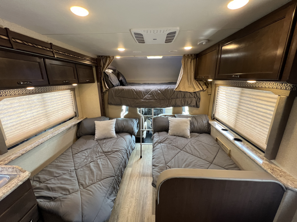 This RV rental interior offers three comfortable sleeping areas: an overhead bunk and two floor-level beds, perfect for groups.. Thor Motor Coach Freedom Elite 2017