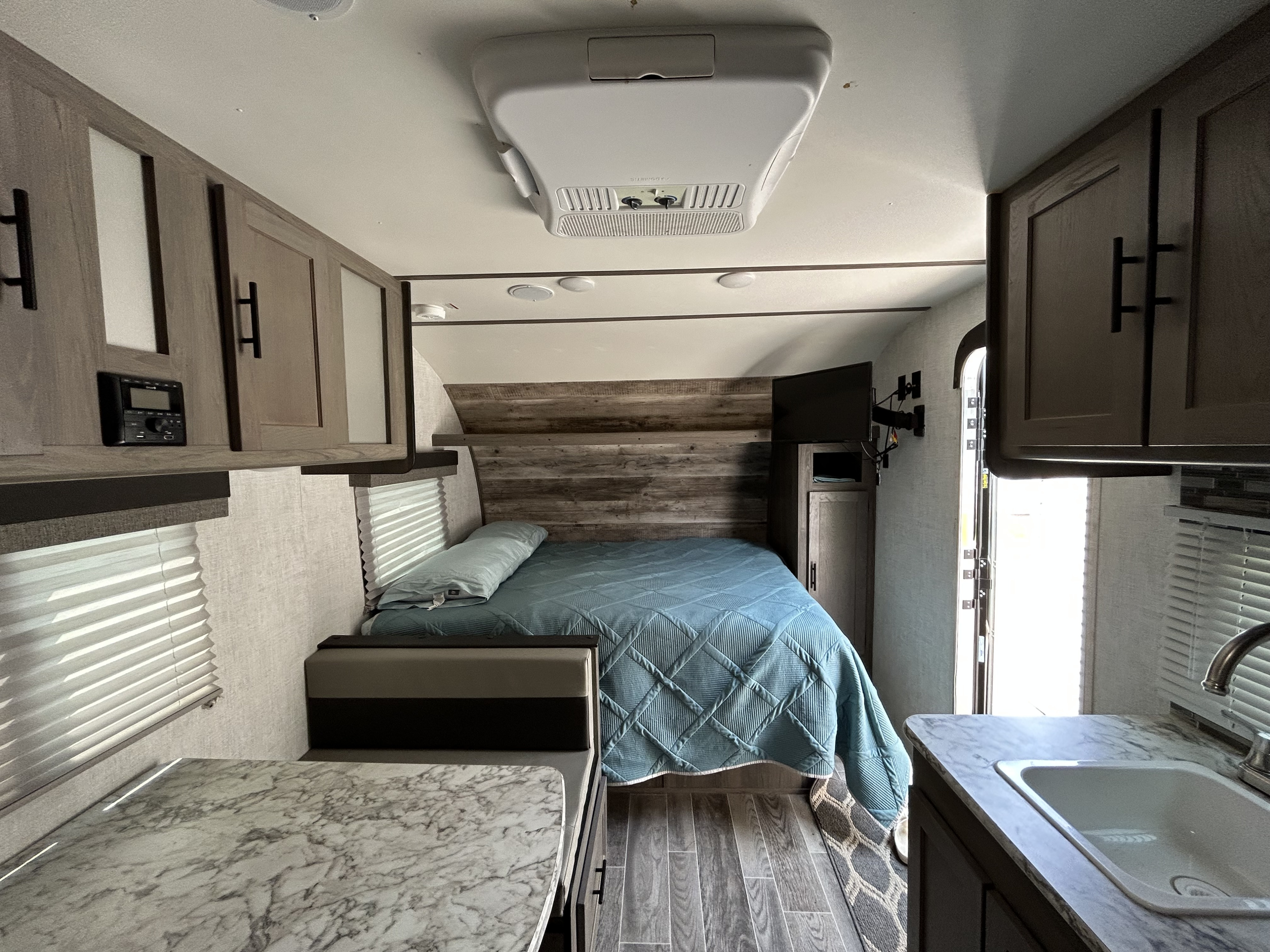 RV rental interior with a cozy bed, dinette, modern cabinetry, and compact kitchen sink area, ready for travel.. Gulf Stream Ameri-Lite Super Lite 2021