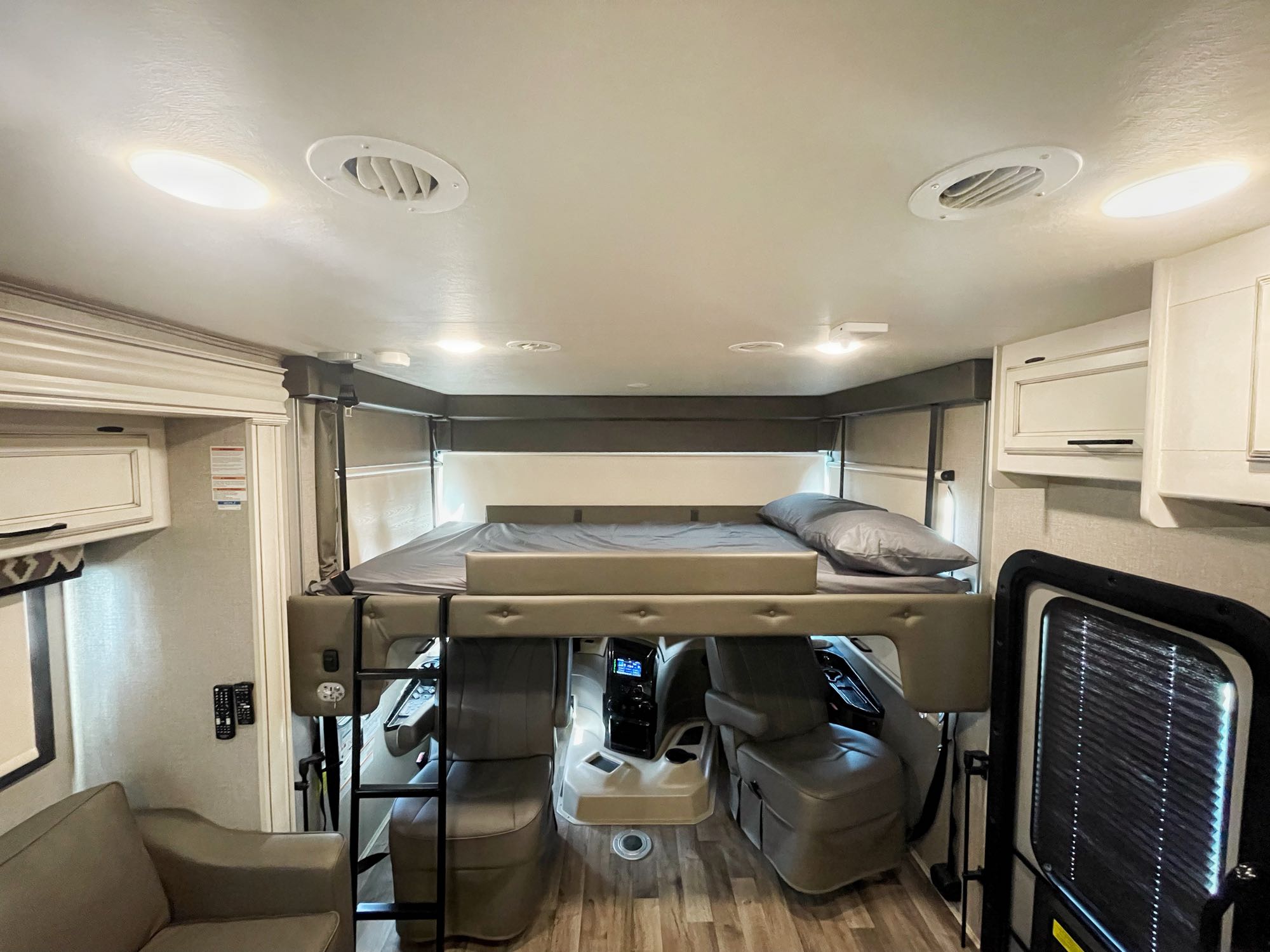 This spacious RV rental interior features a cozy overhead bunk bed, driver's area, and modern decor for comfortable travel.. Jayco Alante 2020