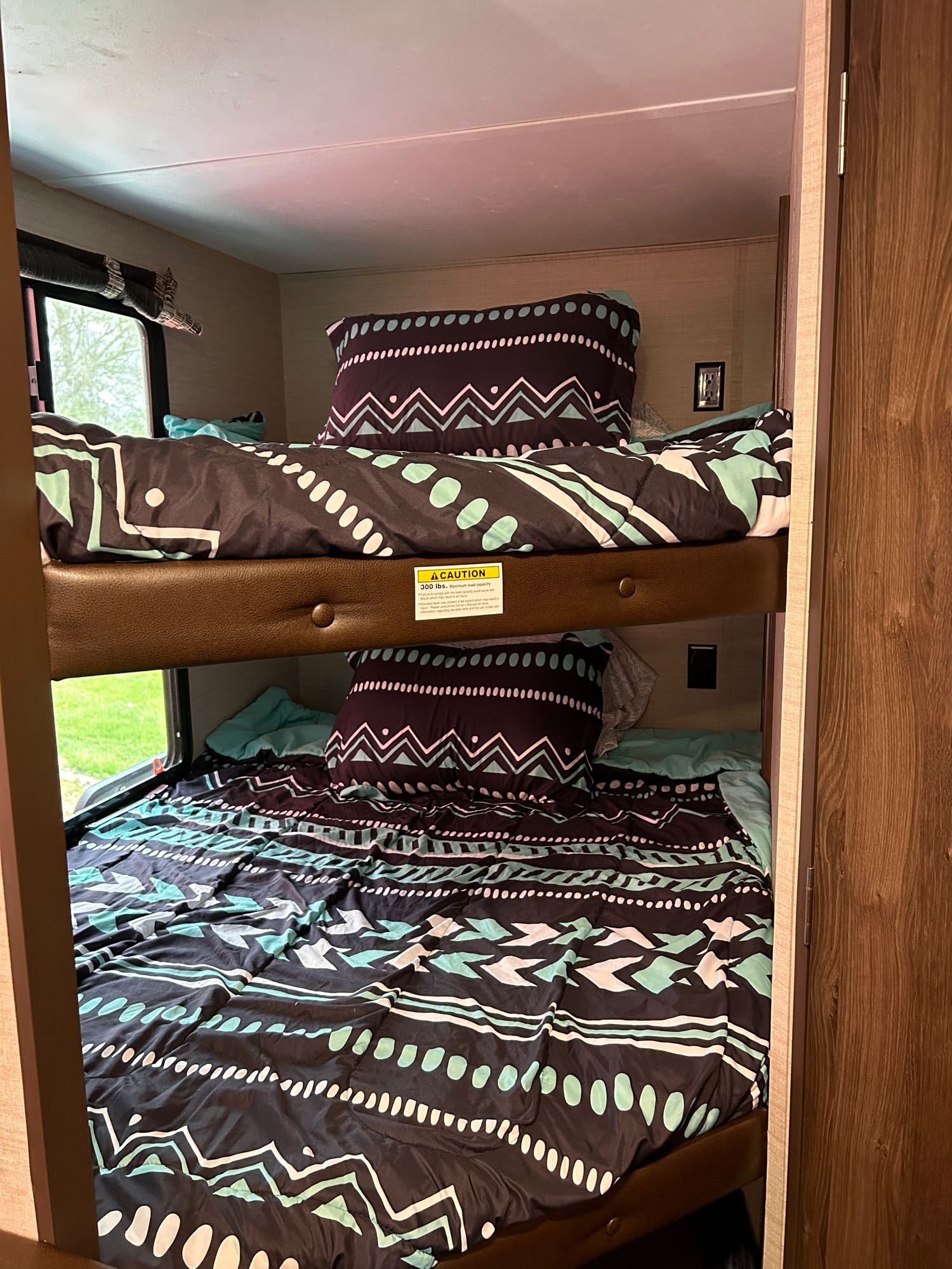 Experience comfort in this RV rental's cozy bunk beds. Features colorful tribal-patterned bedding and a window view.. Keystone RV Bullet Crossfire 2017