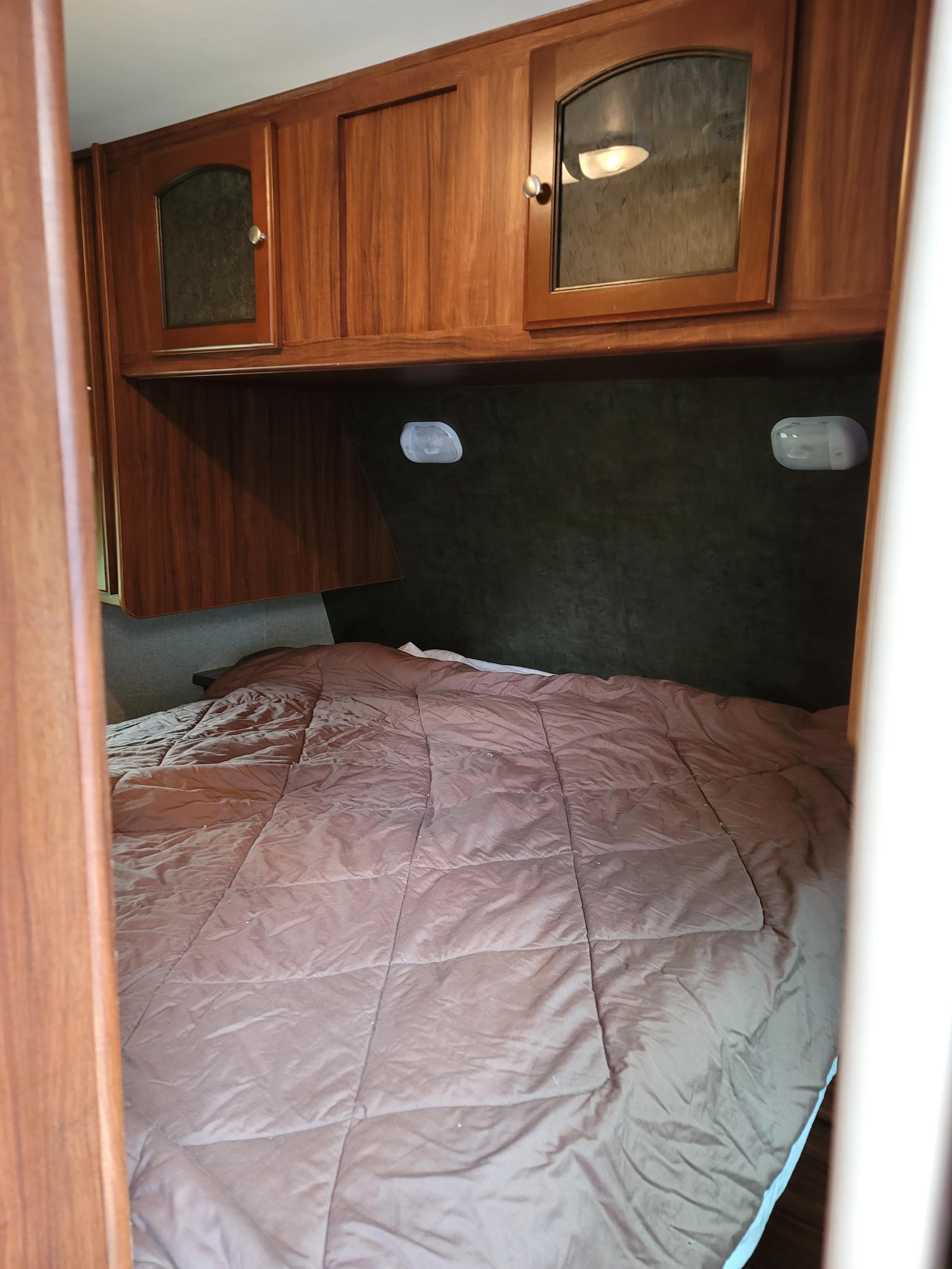 Queen size primary bed with privacy curtains and storage.. Heartland RVs North Trail 2014