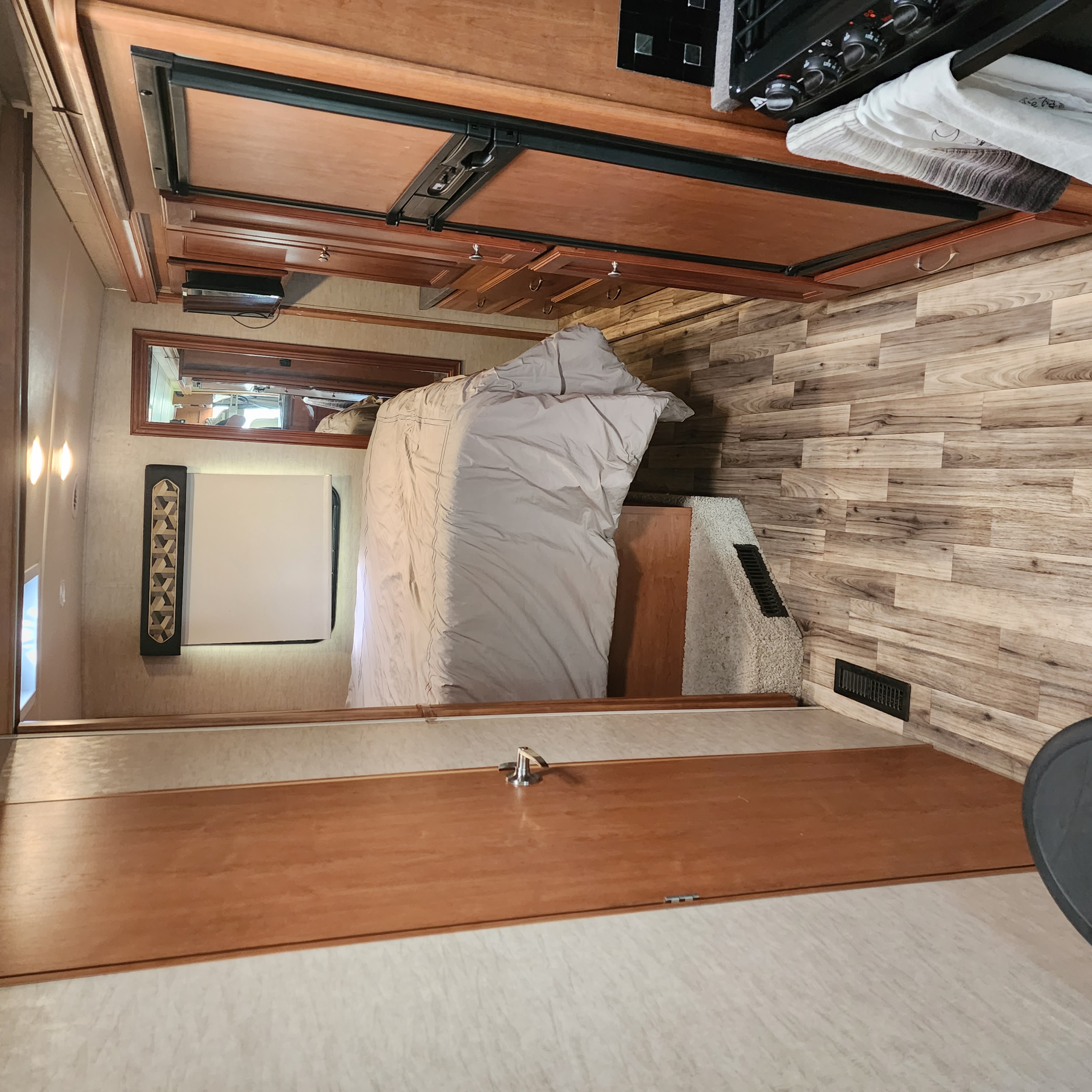 Cozy RV rental interior showcasing a bed, compact kitchen with fridge & stove, and wood-look flooring.. Winnebago Vista 2017