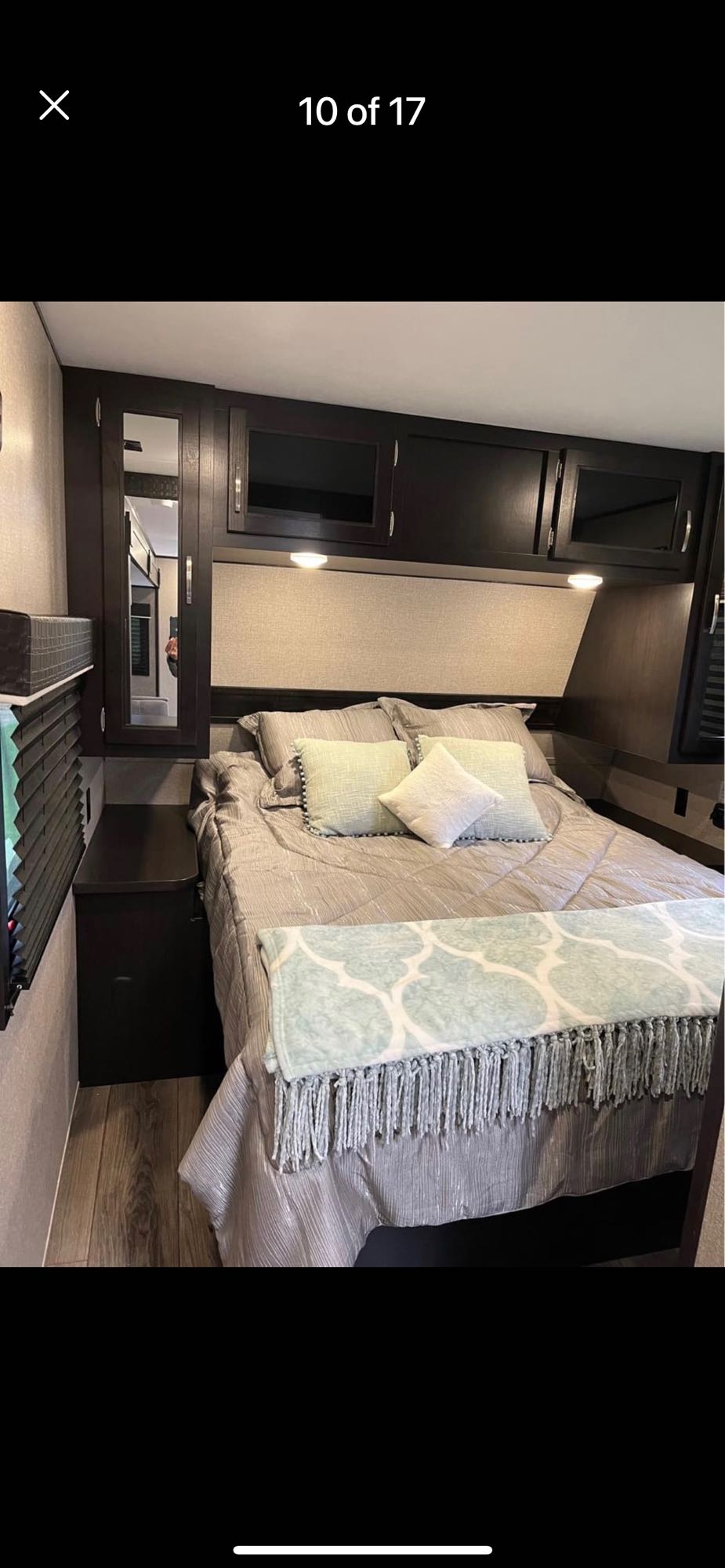 Cozy RV rental bedroom with a queen bed, stylish gray and blue decor, overhead storage, and warm lighting for your journey.. Jayco Jay Flight 2020