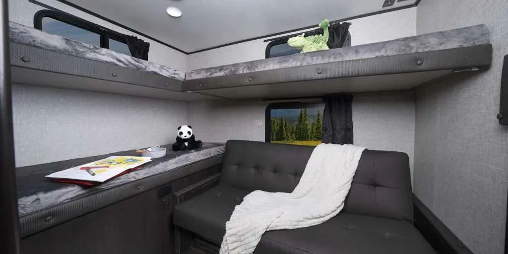 This RV rental offers a cozy bunkhouse with two upper bunks, a lower bed/sofa, and scenic window views.. Jayco Jay Feather 2021