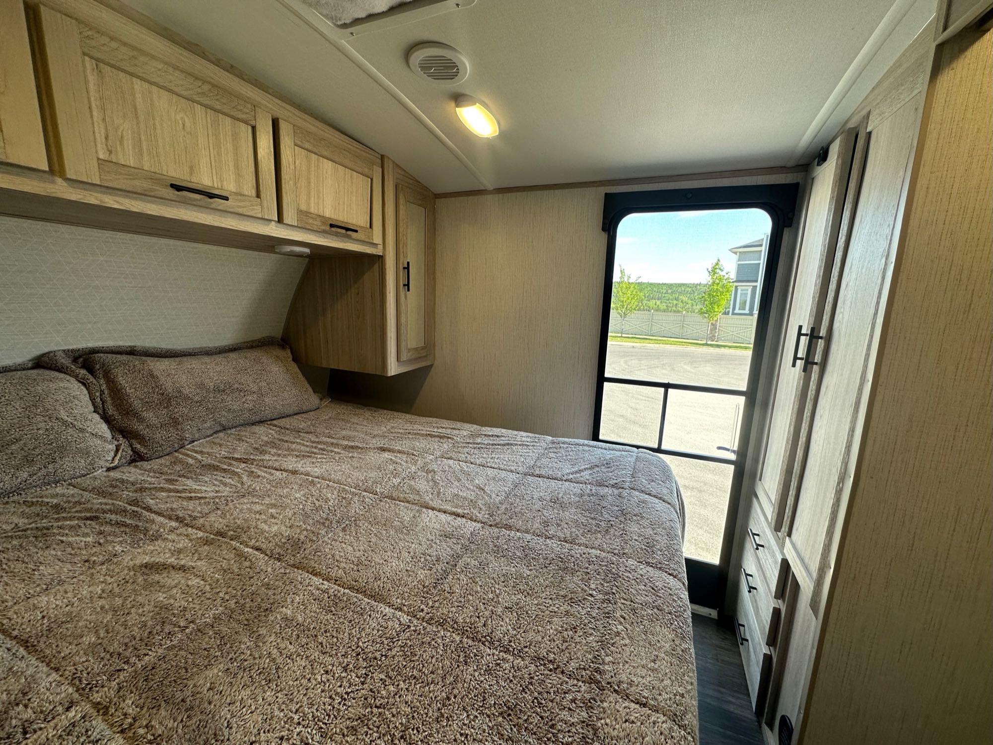 Cozy RV rental bedroom with shaggy brown bedding, light wood cabinets, and a bright window view.. Cruiser RV Shadow Cruiser 2022