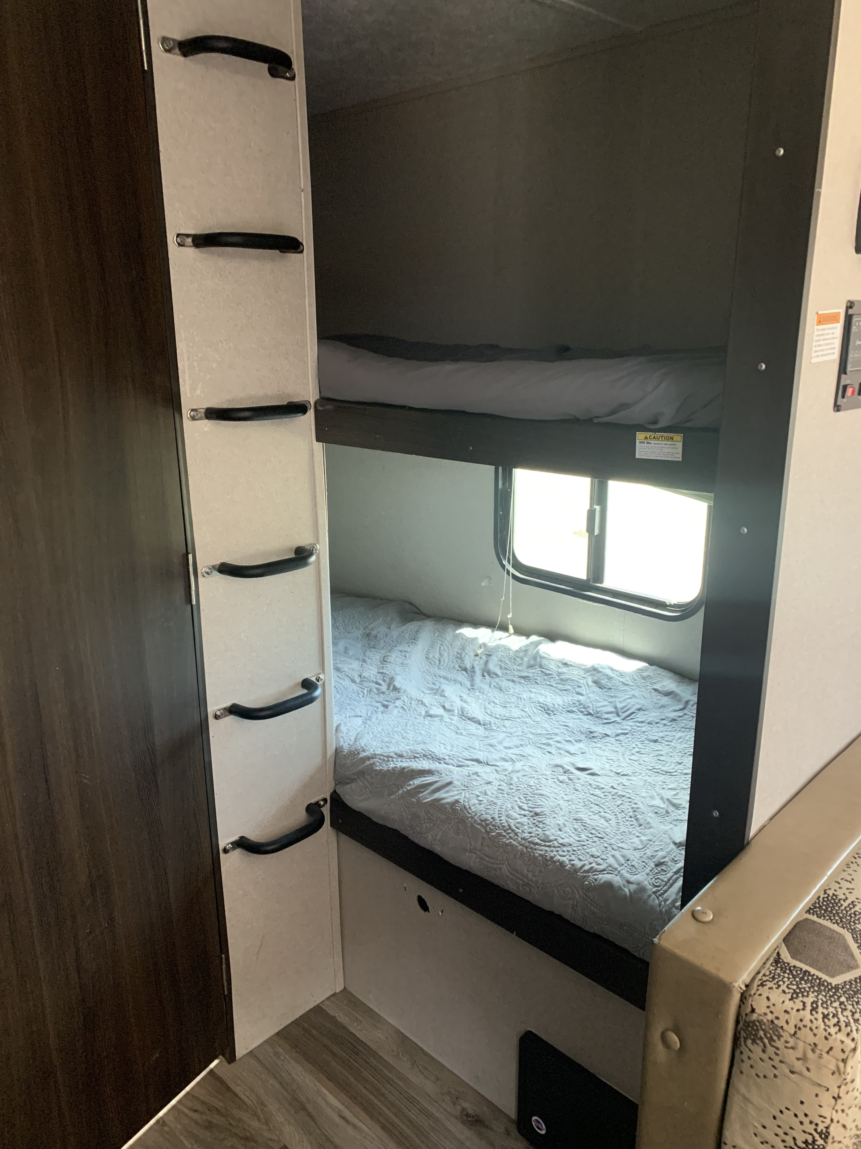 Inside an **rv rental**, a cozy bunk bed area is visible with two beds, a window, and a built-in ladder.. Keystone RV Springdale 2018