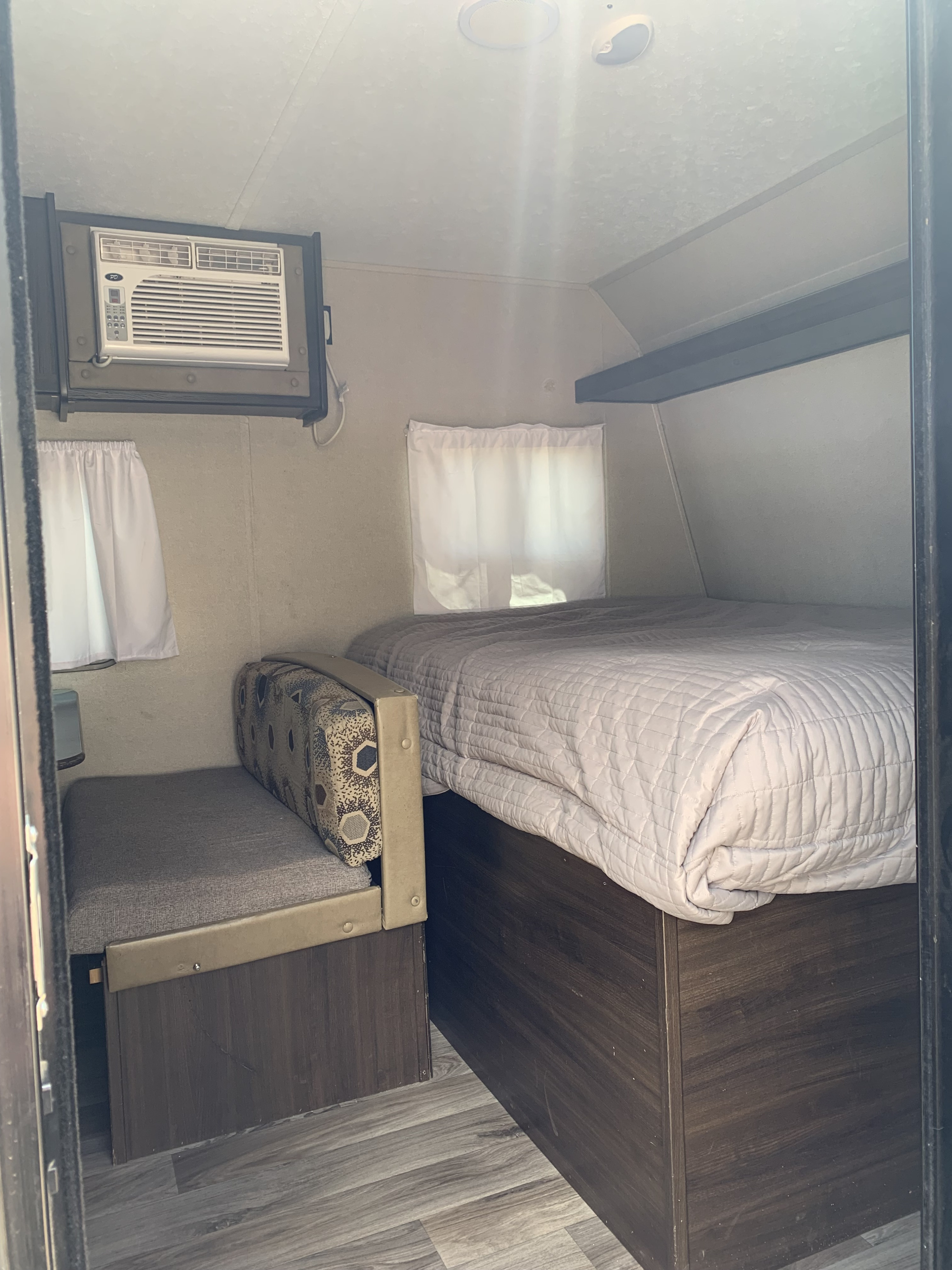 Cozy RV rental interior with a comfy bed, functional AC unit, and compact bench seating for your travels.. Keystone RV Springdale 2018