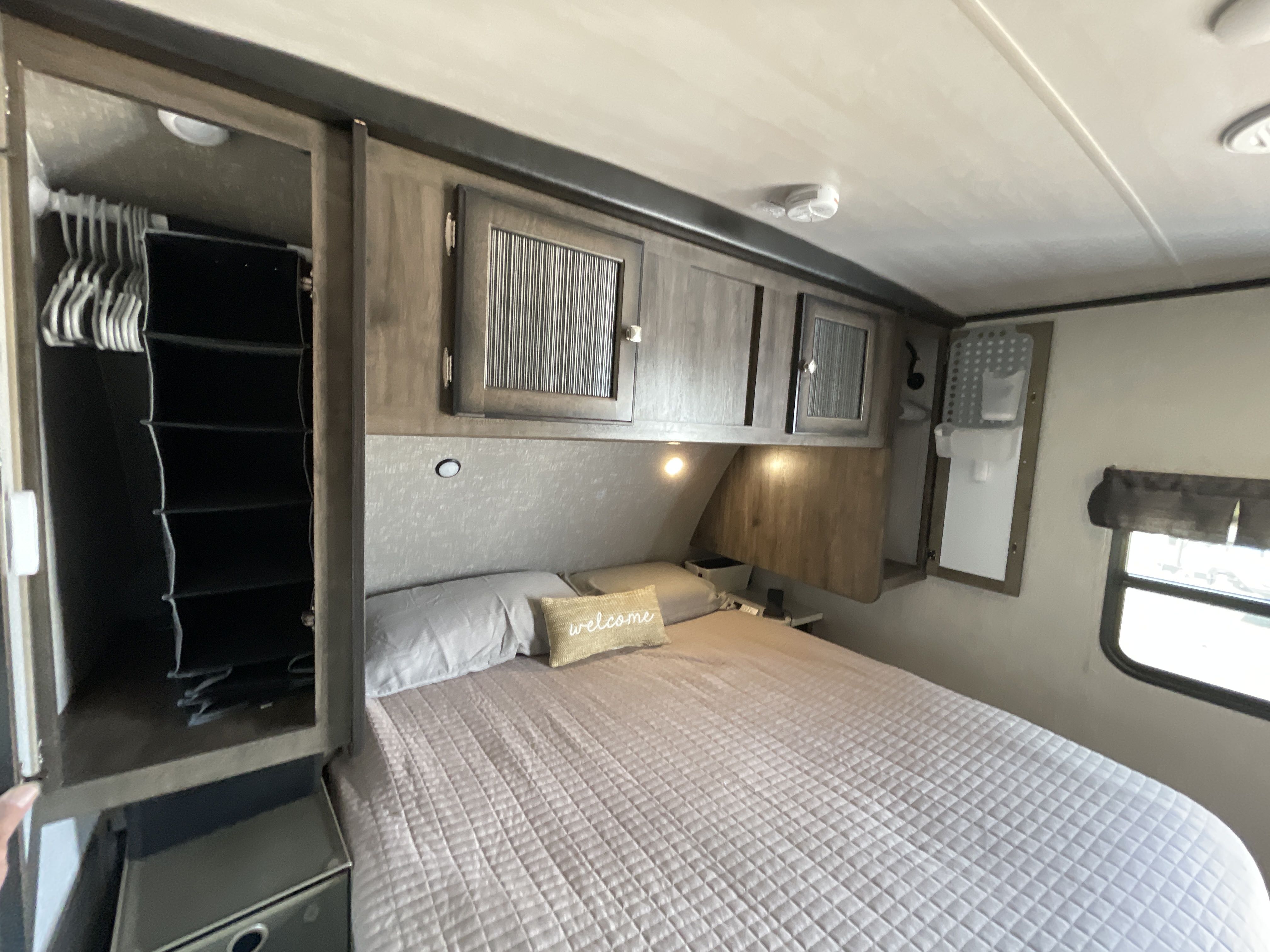 This spacious RV rental bedroom offers a comfortable bed, ample overhead cabinets, and a convenient wardrobe.. Heartland RVs Mallard 2019
