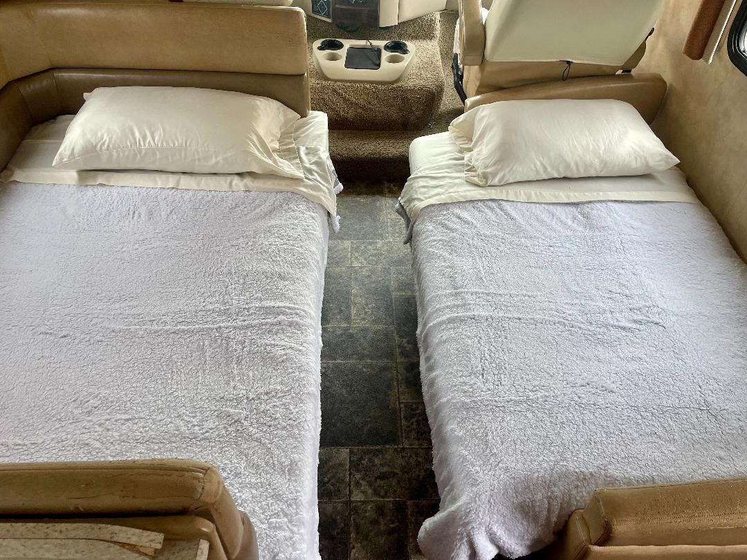 Cozy RV rental interior showcasing two prepared single beds with white bedding, ideal for travel comfort.. A.C.E. A.C.E. Motorhome 2014