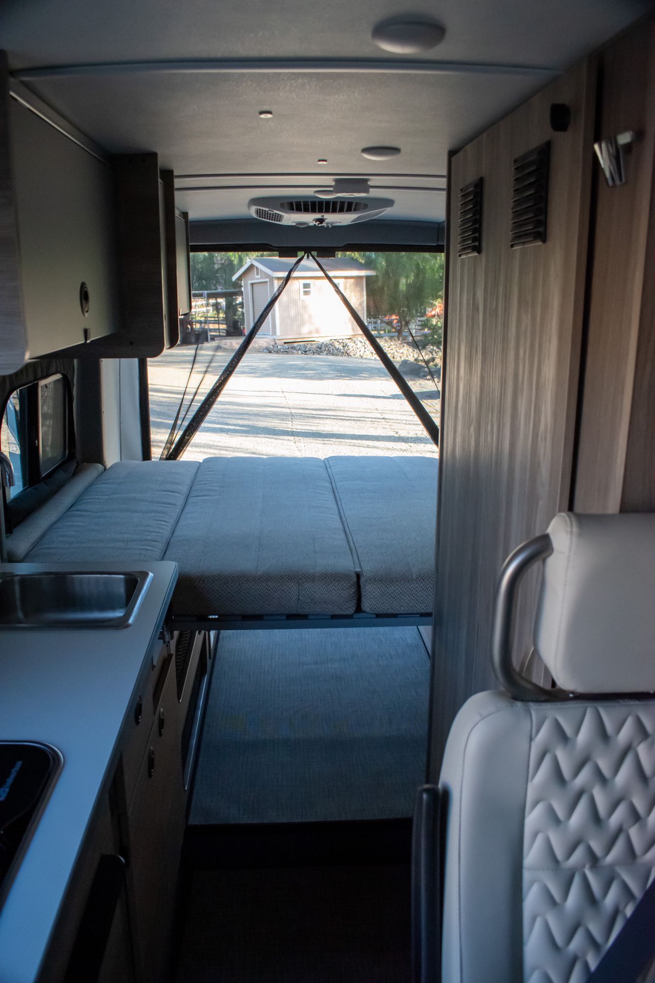 RV rental interior: A versatile space featuring a convertible bed, kitchen area, and open rear doors with an outdoor view.. Winnebago Solis 59PX 2023