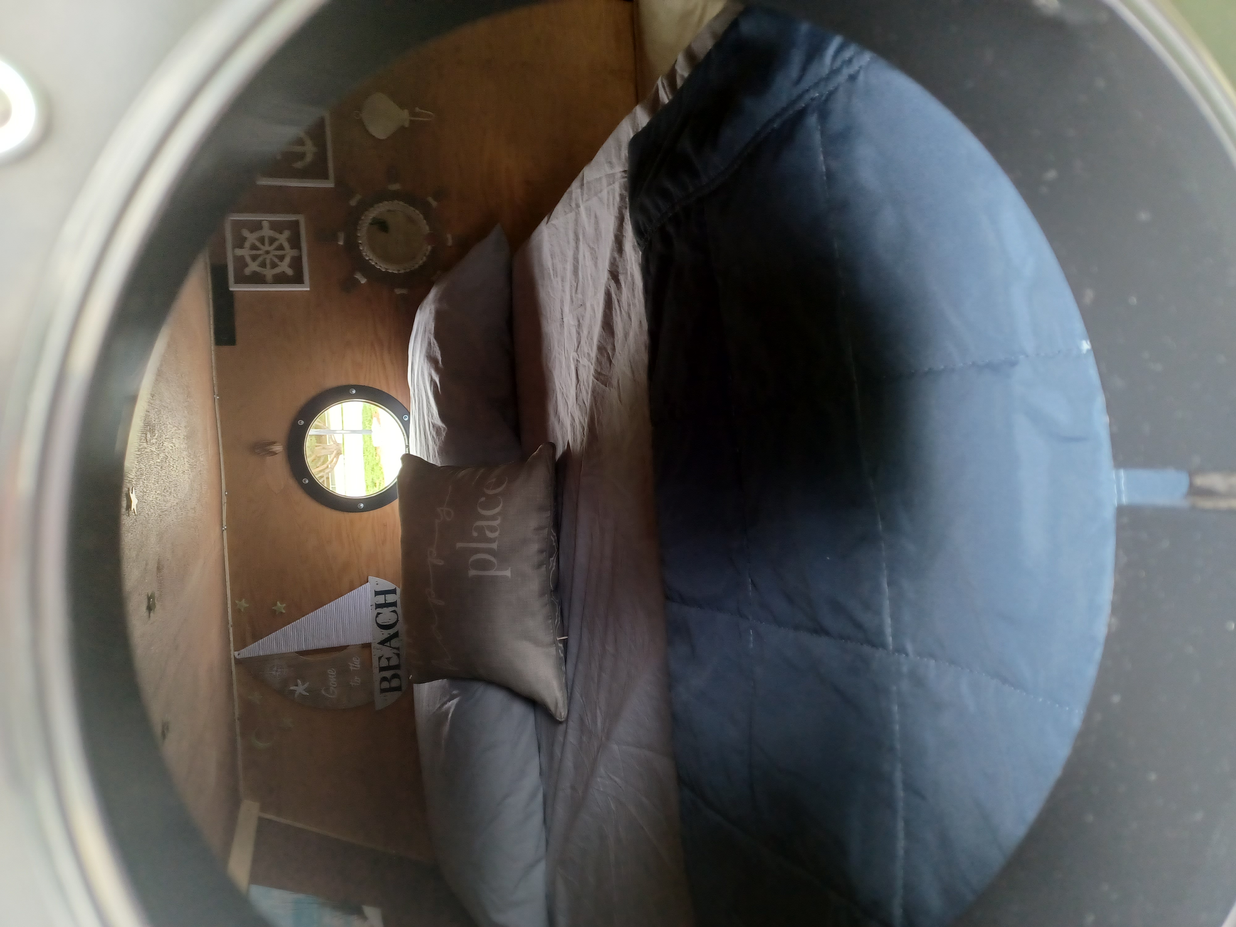 Cozy RV rental interior: bed with blue comforter, 'place' pillow, porthole window, and nautical wall decor.. Bend Teardrop Family Style 6'x12' 2022