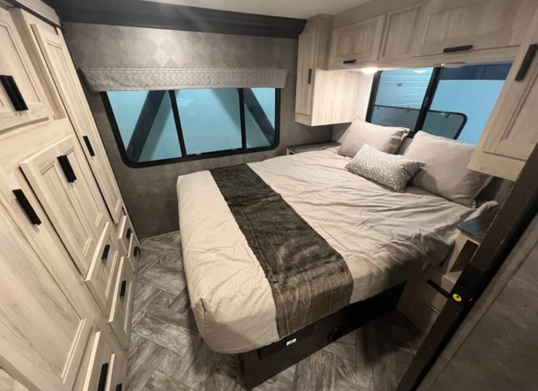RV bedroom interior showing a comfortable bed, overhead cabinets, and dresser, perfect for your RV rental journey.. Forester LE 2022