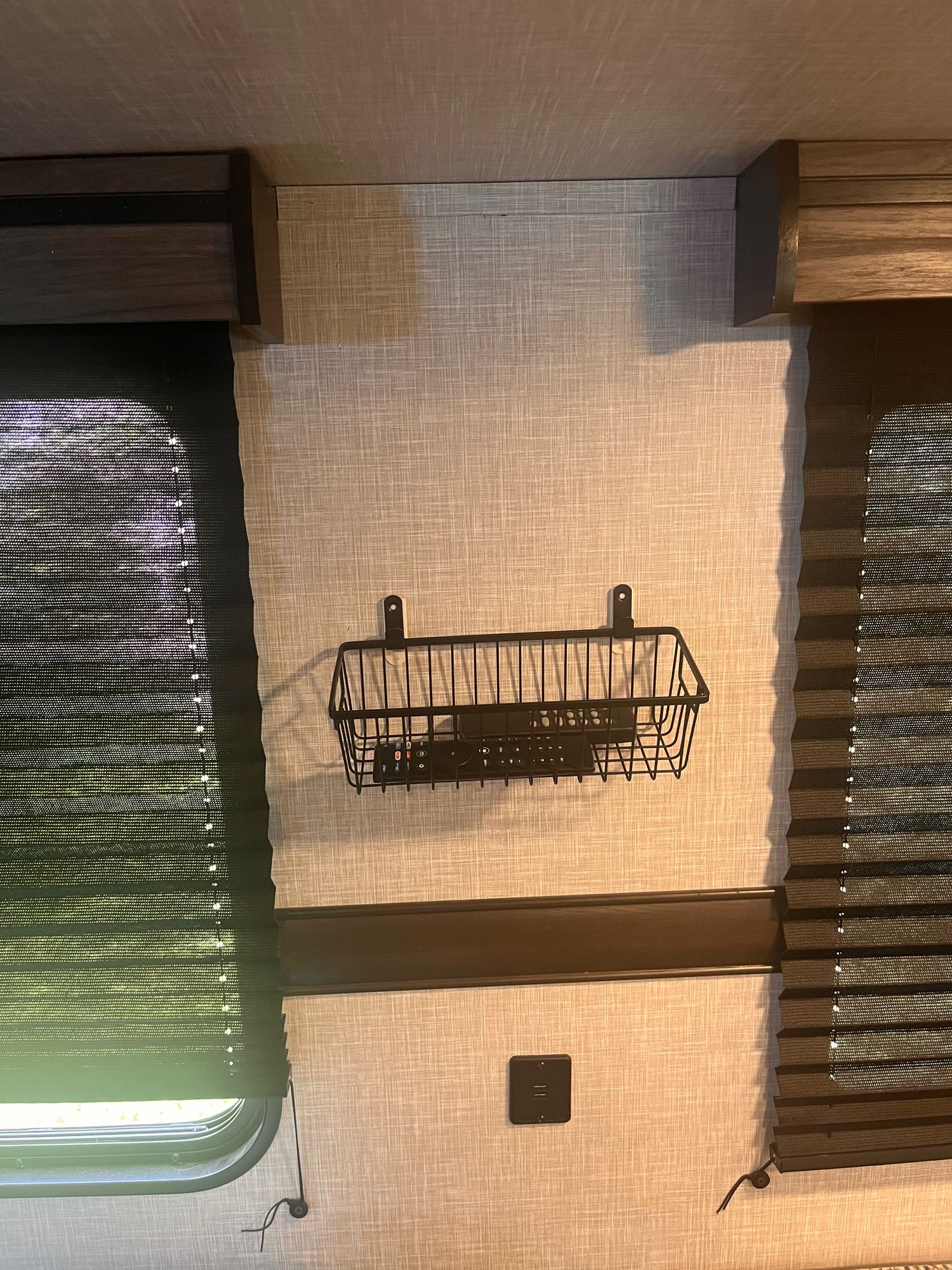 RV rental interior: Dark pleated blinds, wooden valances, a wire basket with remotes, and textured walls. Functional storage.. Crossroads RV Zinger Lite 2022