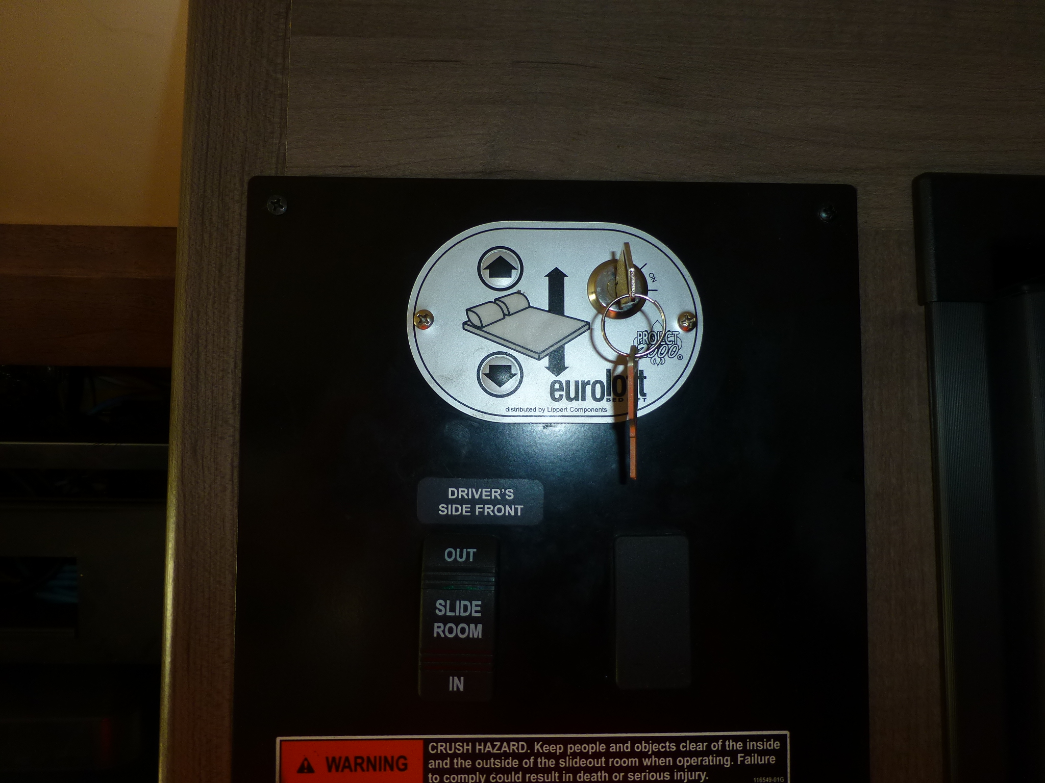 RV rental control panel: operate the slide-out room and EuroLoft bed lift, with crush hazard warning.. Winnebago Vista 2020