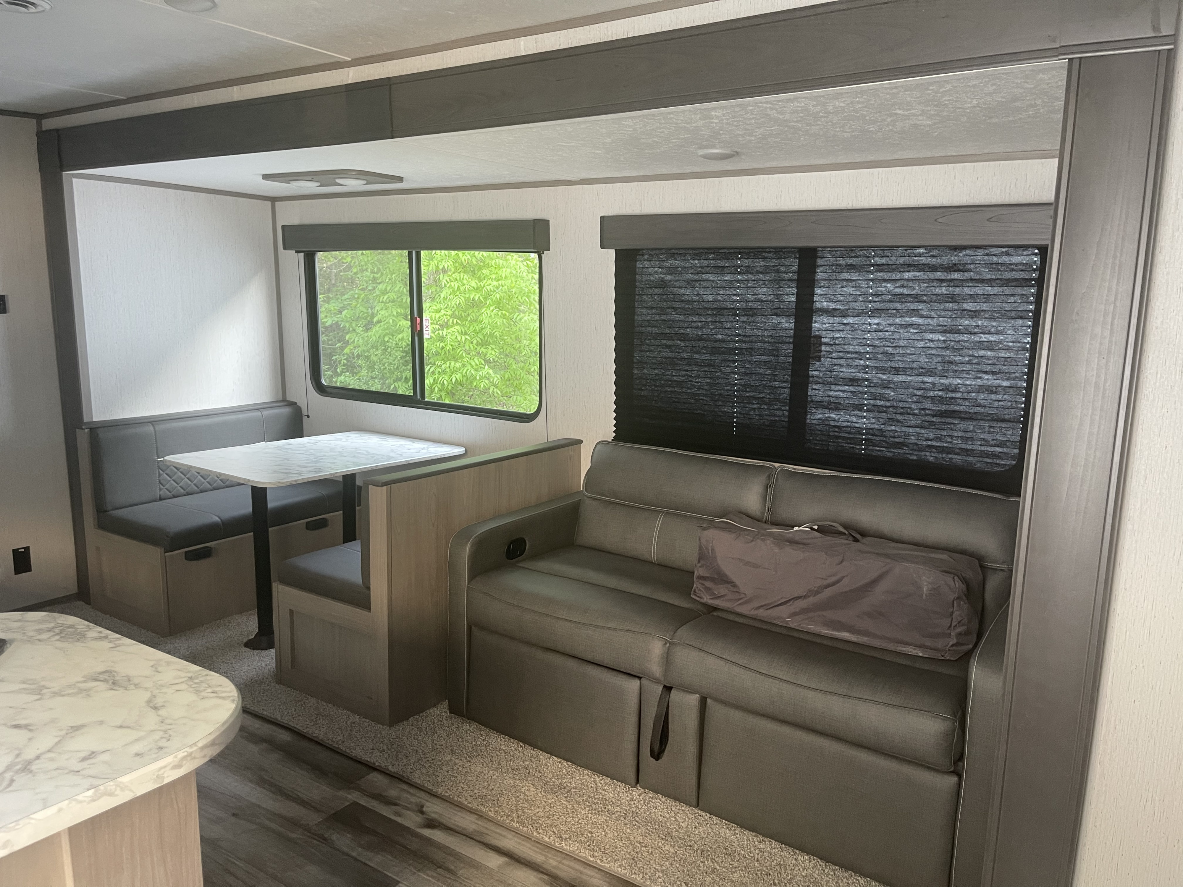 Inside a modern RV rental: a cozy living area with a dining booth and convertible sofa.. Coleman Dutchman Lantern 2022