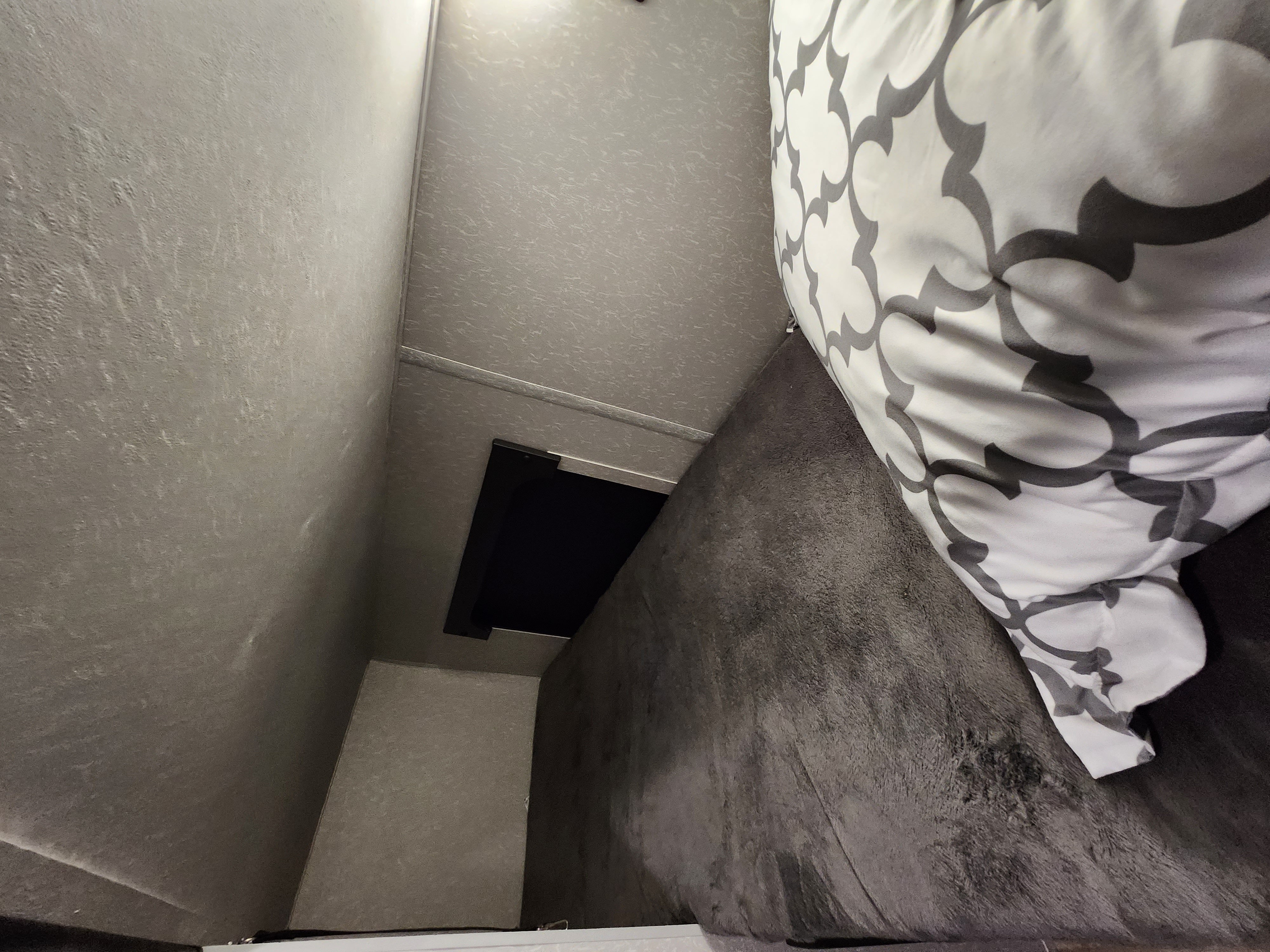 RV rental: Inside, a cozy bed with gray patterned pillow, soft dark blanket, and light textured walls define the sleeping area.. Forest River Cherokee Wolf Pup 2022