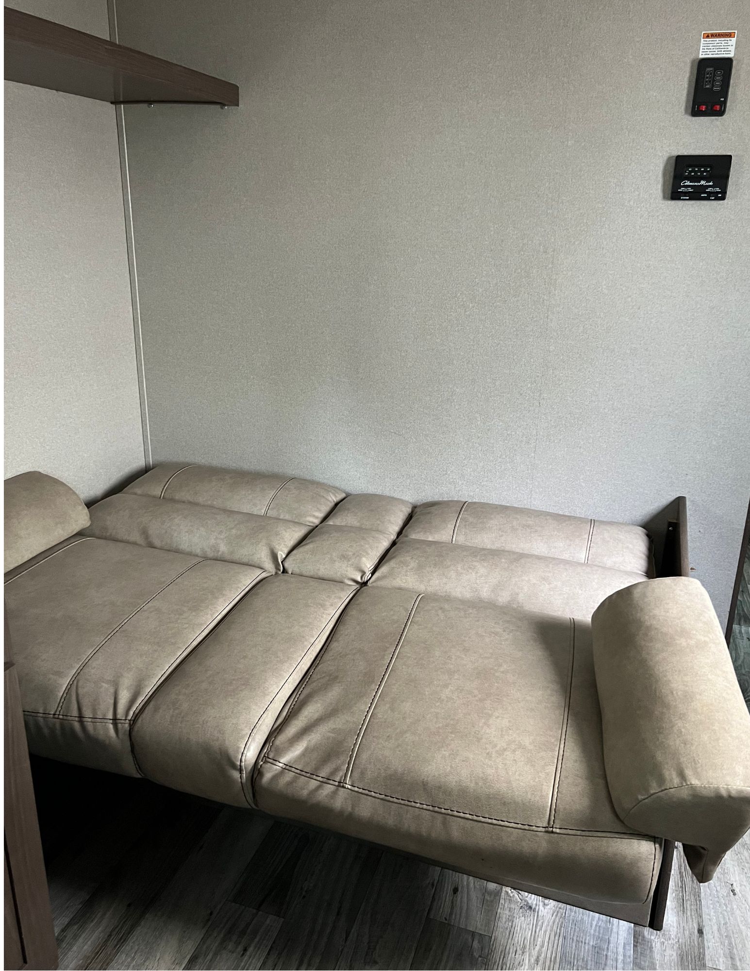 RV rental interior featuring a tan pull-out sofa configured as a bed, with wall controls visible above.. Keystone RV Hideout 2018