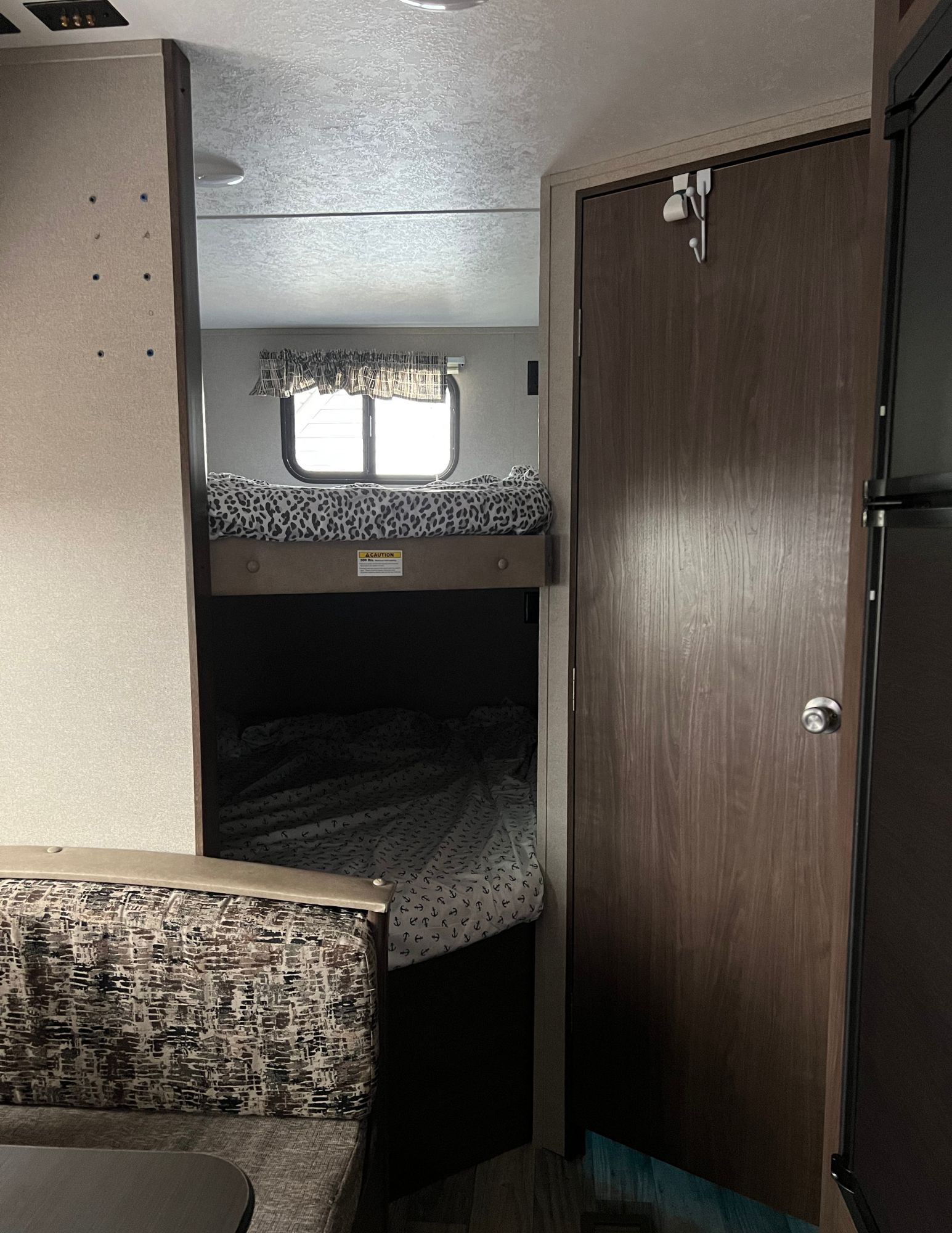 Inside this RV rental: View of bunks with window, dinette seating, and an interior door.. Keystone RV Hideout 2018