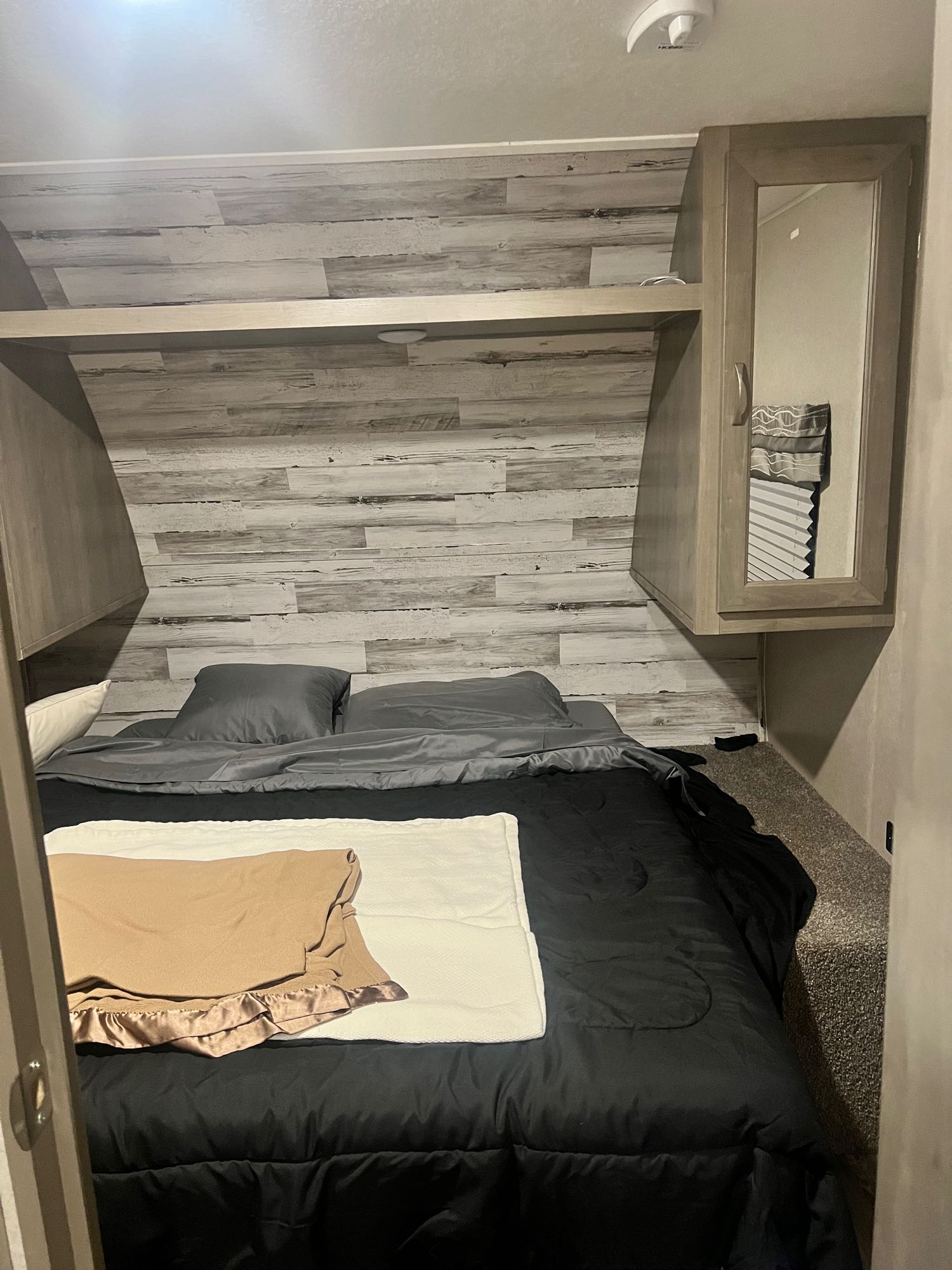 Cozy RV rental bedroom with comfortable bed, wood-paneled walls, and convenient overhead storage.. Forest River Palomino Puma XLE 2019