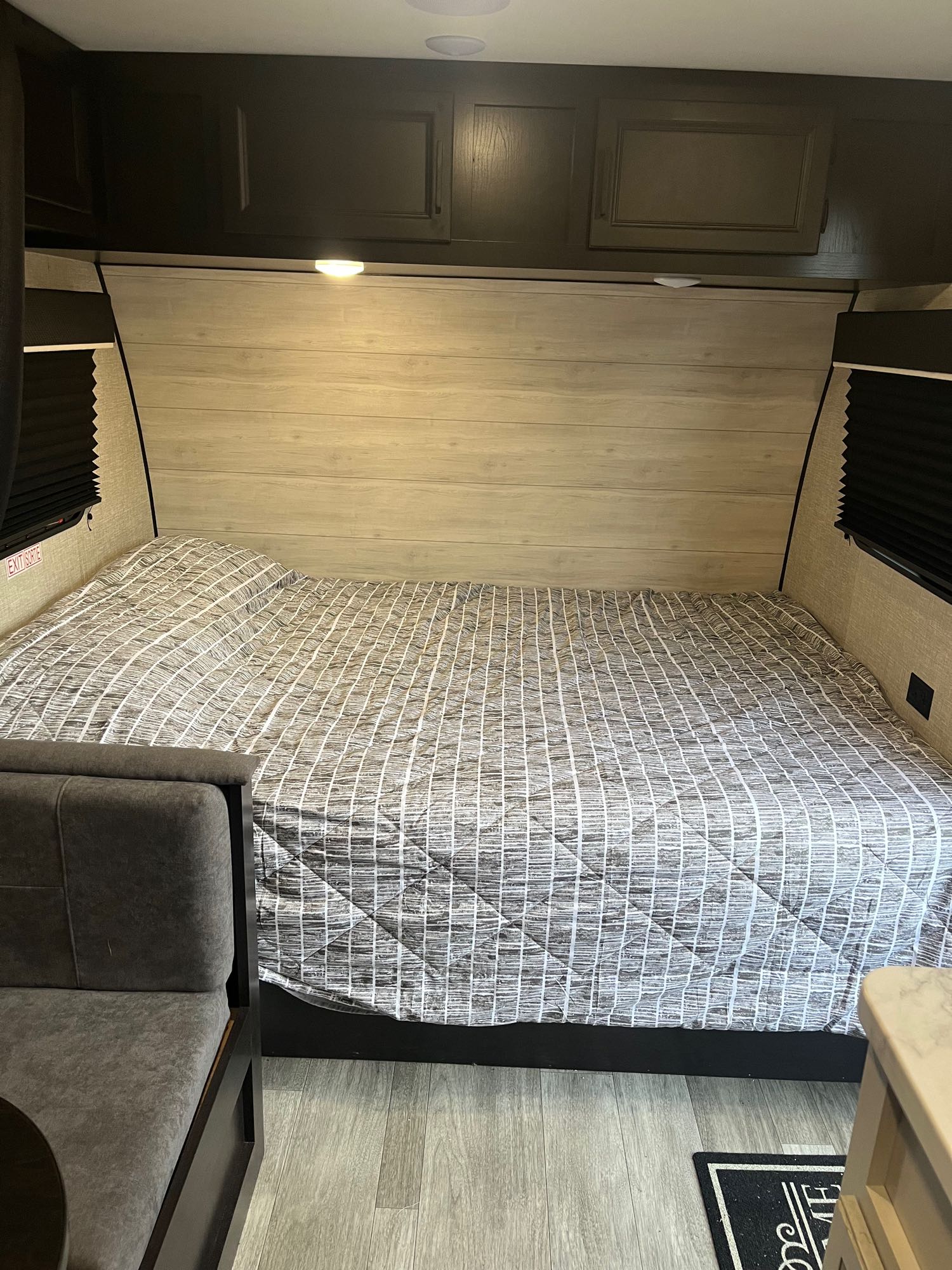Cozy RV rental bedroom featuring a large bed with a gray comforter, overhead storage, and dinette seating.. Jayco Jay Flight SLX 2023