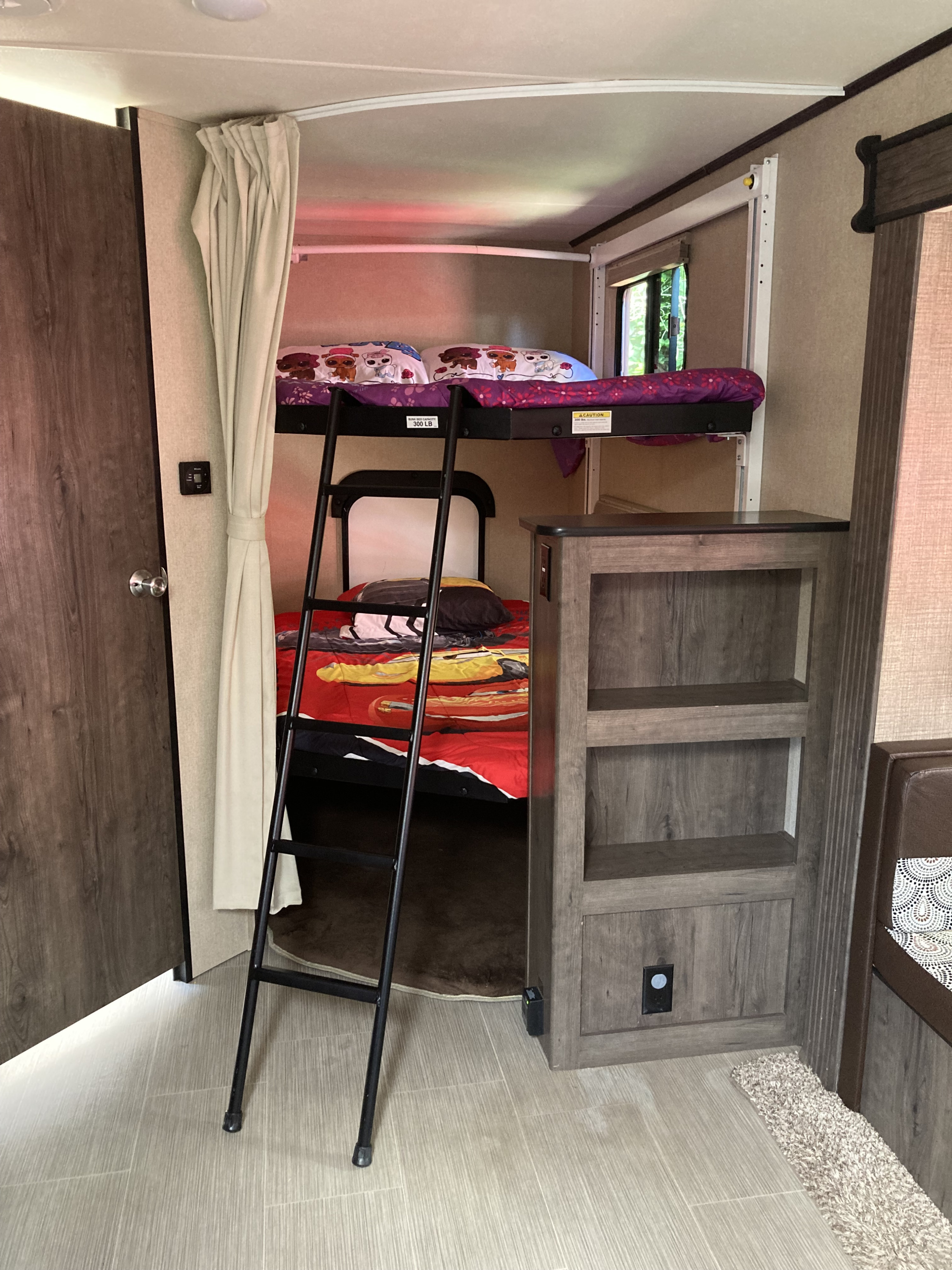 RV rental bunk beds: A cozy space with a ladder, colorful bedding, privacy curtain, and built-in storage.. Dutchmen Kodiak Ultimate 2017