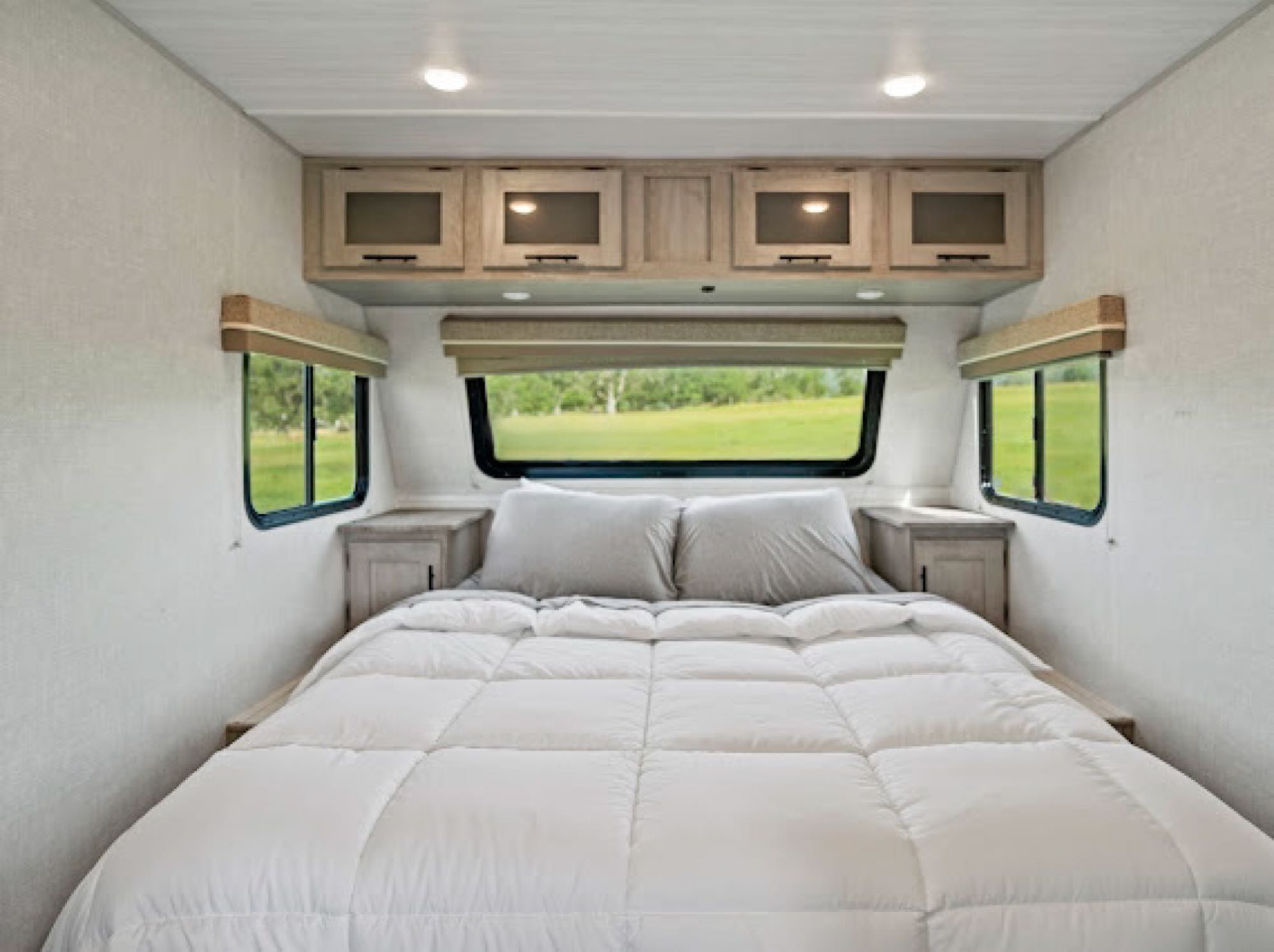 Spacious and cozy RV rental bedroom interior with a comfortable bed, overhead cabinets, and large windows with scenic views.. Forest River Ibex 2021