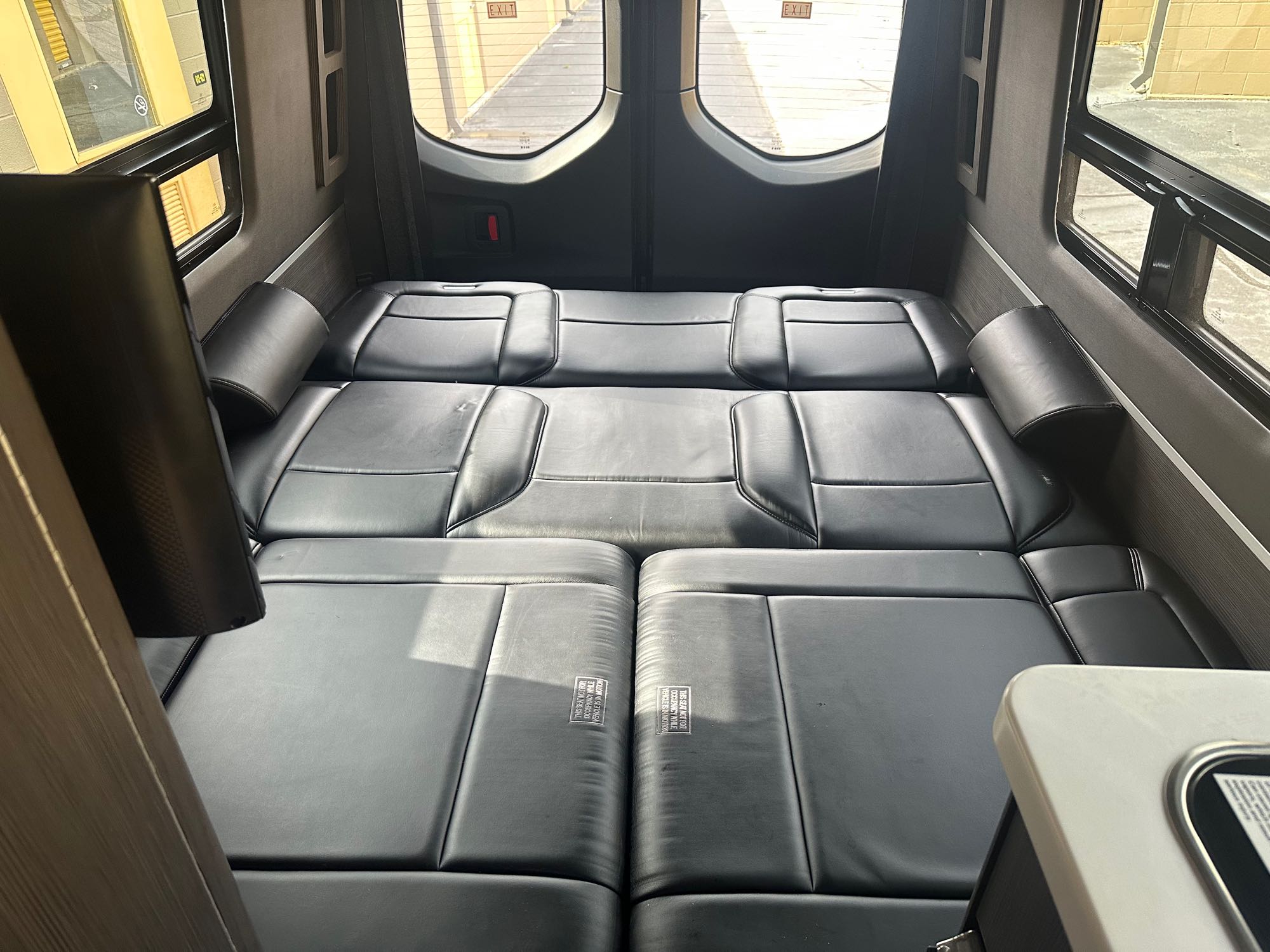 Comfortable rv rental interior: black leather cushions convert to a bed, with side bolsters and large windows.. Airstream Interstate 2020