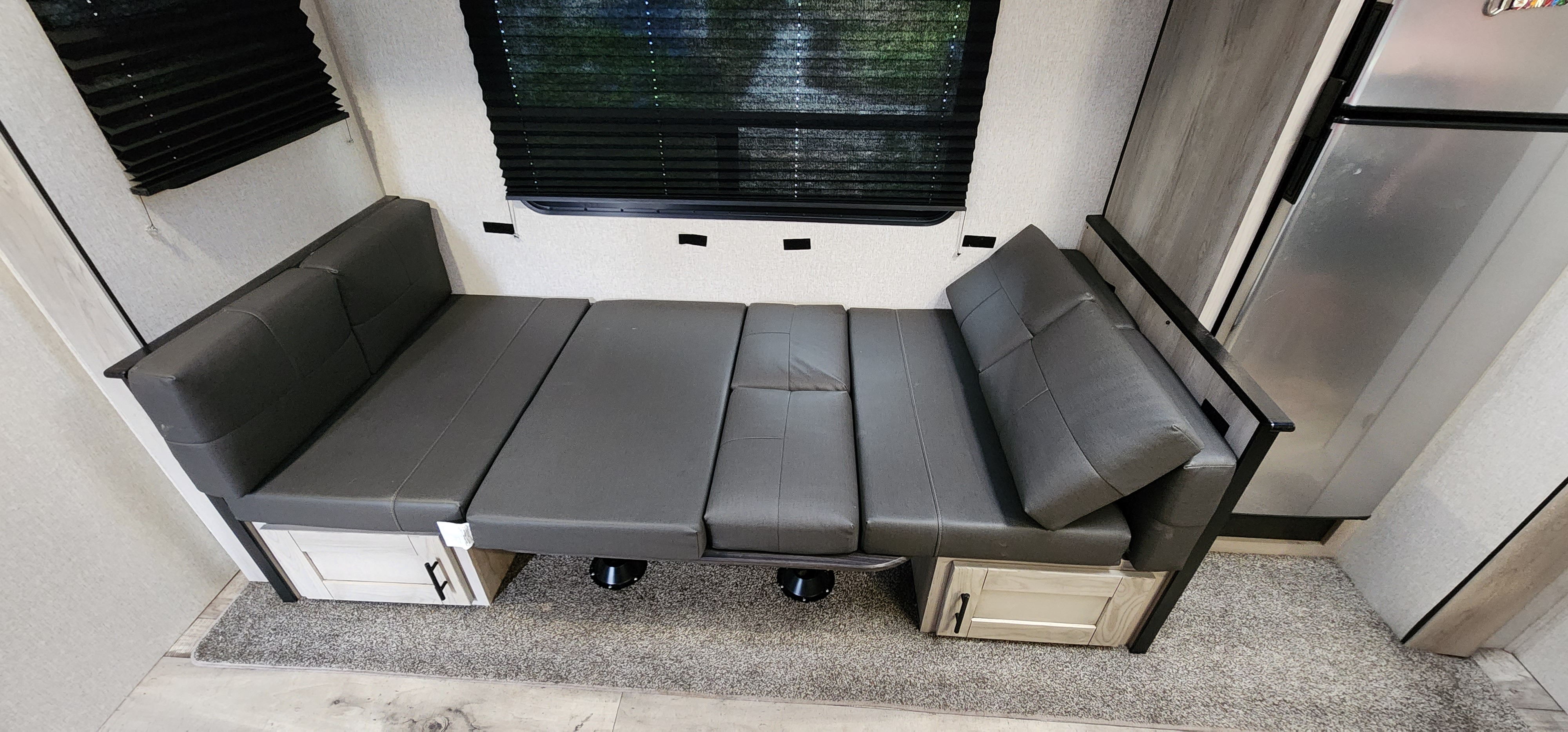 RV rental: Versatile interior featuring a gray convertible dinette/bed with storage, window, and refrigerator.. KZ Connect 2022