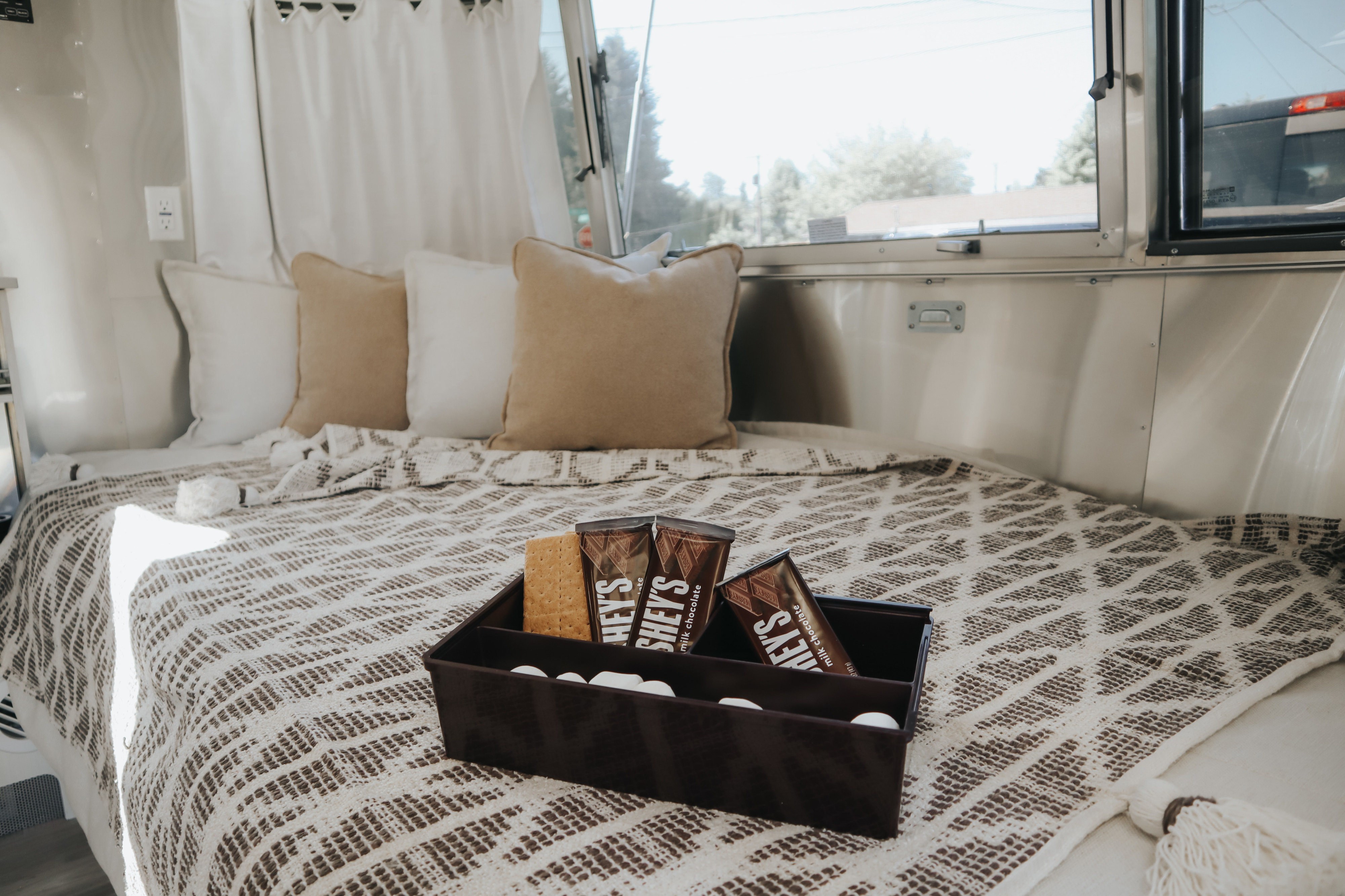 RV rental interior featuring a comfy bed, s'mores supplies, and bright windows.. Airstream Bambi 2023