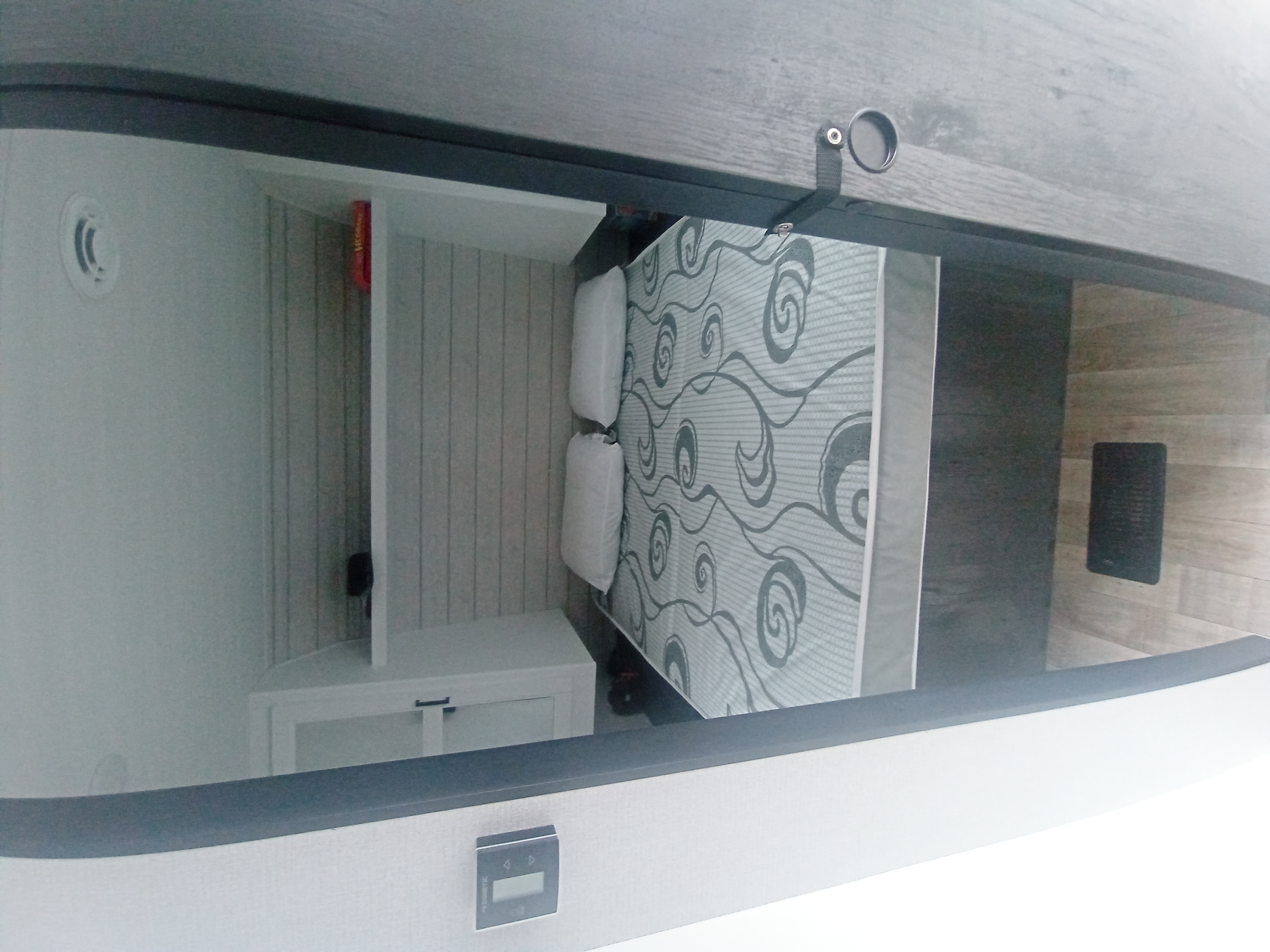 View inside an RV rental's cozy sleeping area, featuring a patterned bed, storage, and vent. Ideal for travel comfort.. Keystone RV Hideout 2022