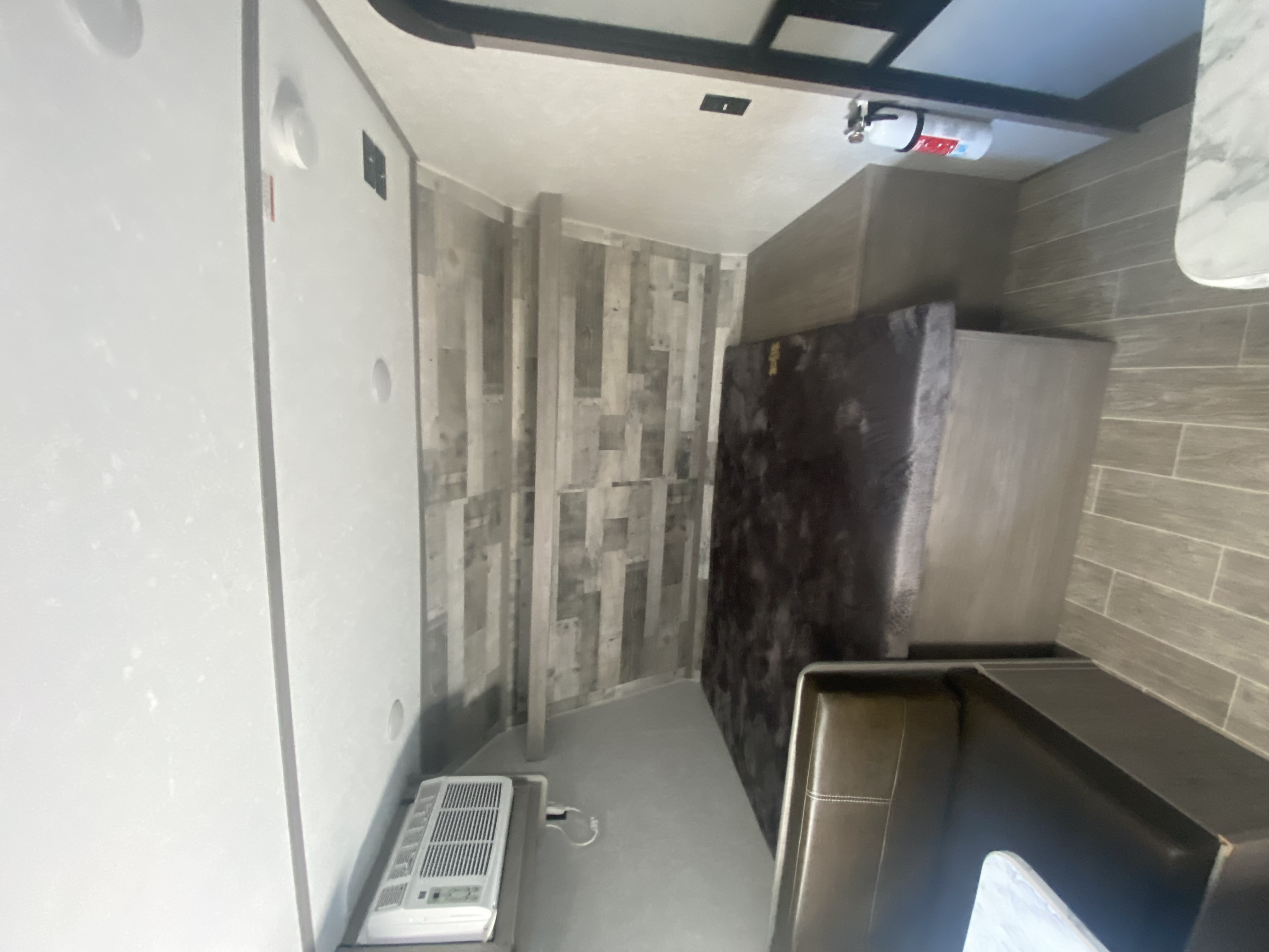 Cozy RV rental interior featuring a convertible dinette/bed, portable AC, and safety essentials like a fire extinguisher.. Dutchmen Coleman Lantern LT 2022